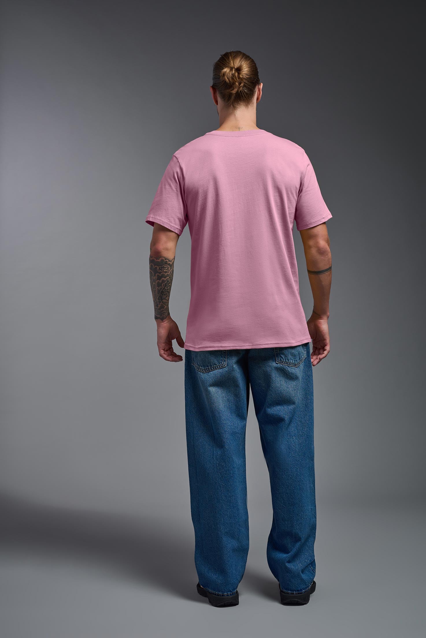 A male model wearing the unisex Organic Soft Cotton T-shirt in the color Himalayan salt pink, made in the USA from 100% GOTS certified organic cotton from a back view. This shirt is unisex, made in the USA, and perfect for bulk screen printing and decorating. #himalayan-salt