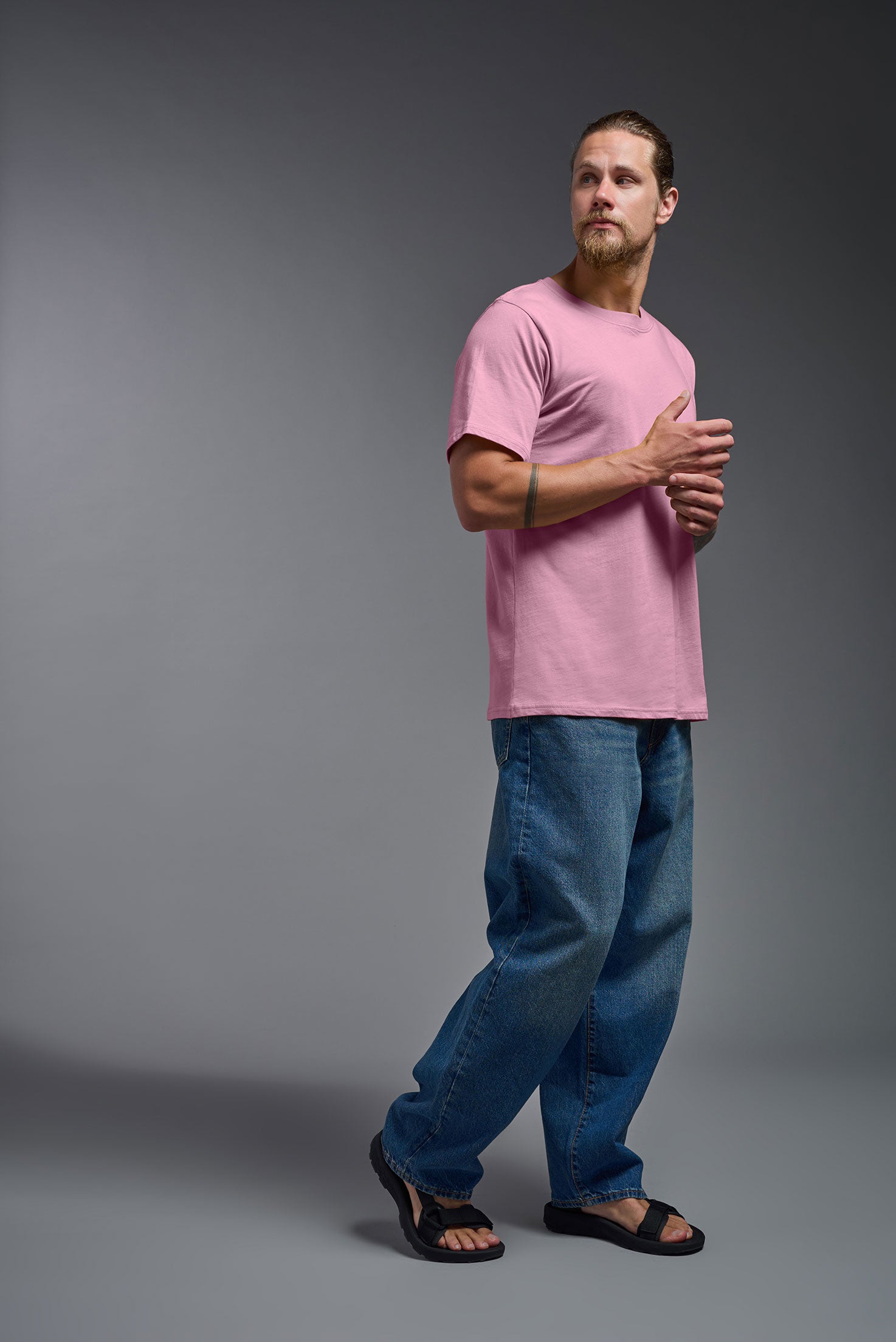 A male model wearing the unisex Organic Soft Cotton T-shirt in the color Himalayan salt pink, made in the USA from 100% GOTS certified organic cotton from a side view. This shirt is unisex, made in the USA, and perfect for bulk screen printing and decorating. #himalayan-salt