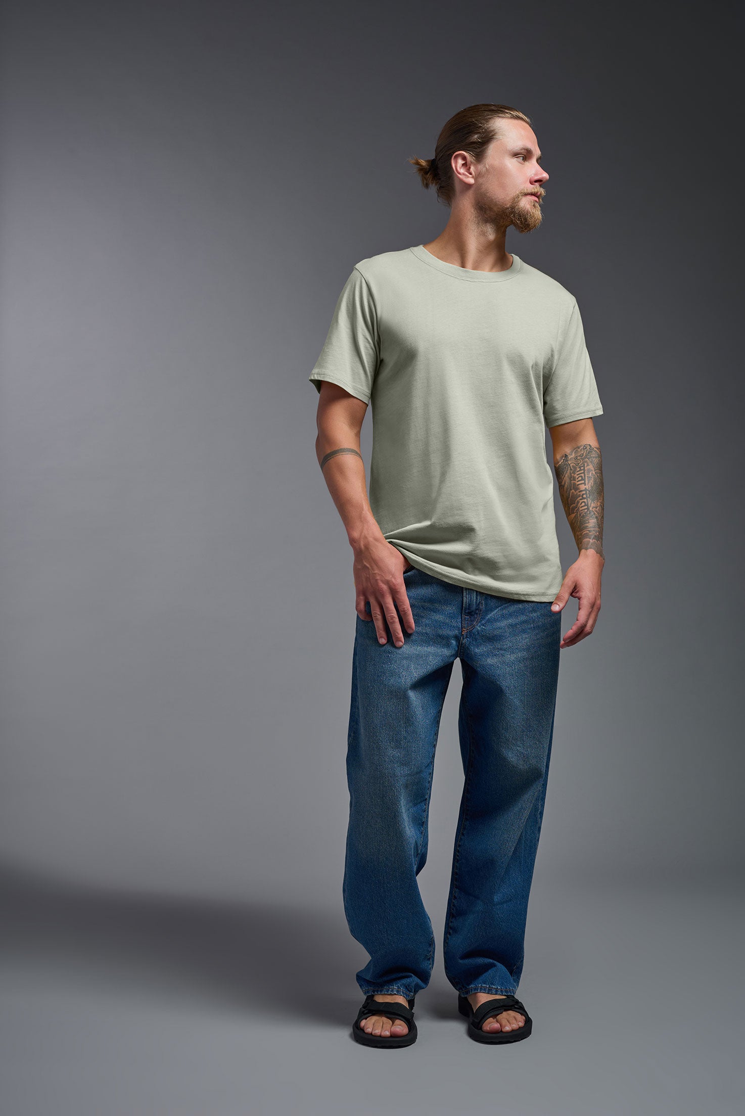 A male model wearing the unisex Organic Soft Cotton T-shirt in the color sage green, made in the USA from 100% GOTS certified organic cotton from a front view. This shirt is unisex, made in the USA, and perfect for bulk screen printing and decorating. #sage