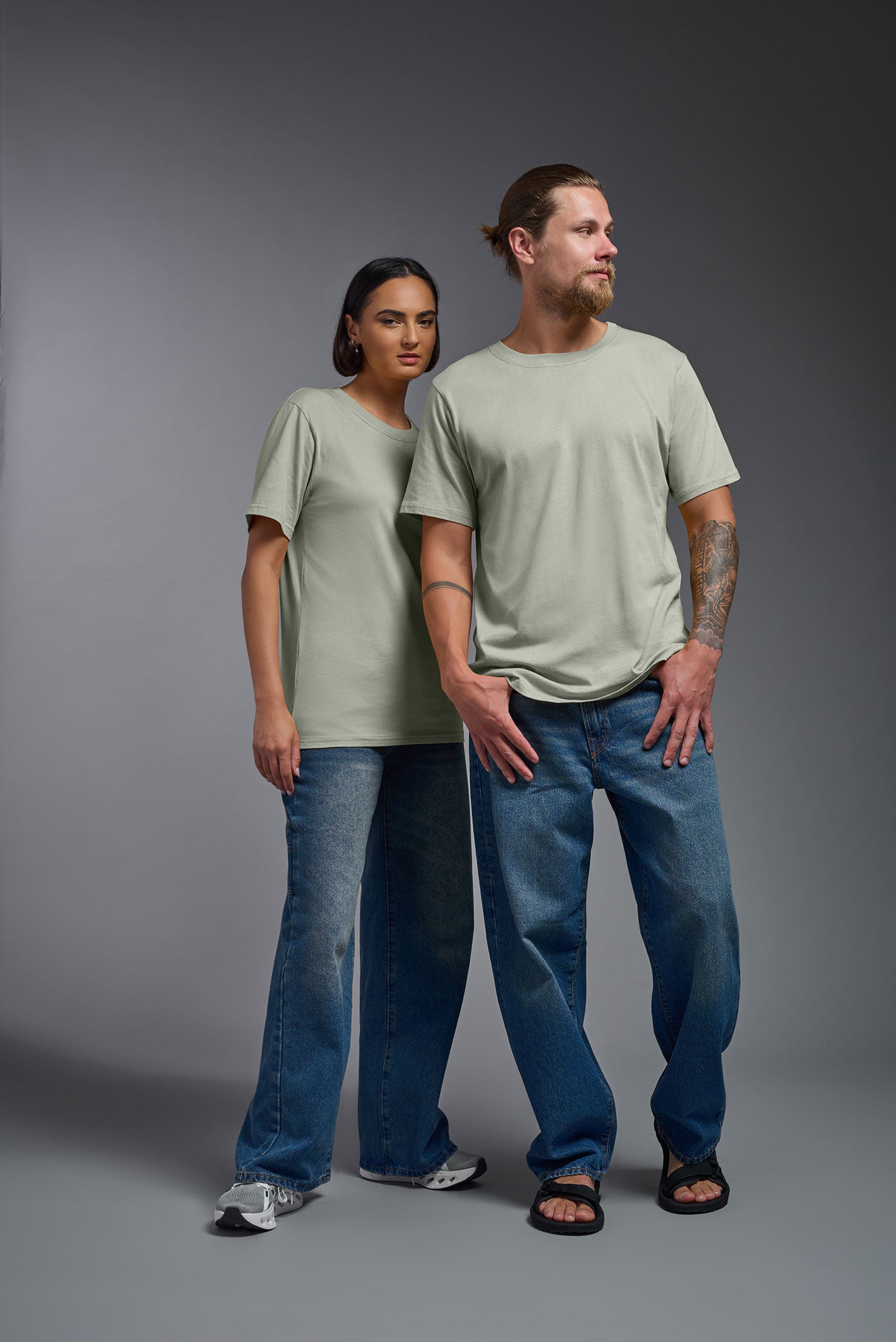 A male and female model wearing the unisex Organic Soft Cotton T-shirt in the color sage green, made in the USA from 100% GOTS certified organic cotton from a front view. This shirt is unisex, made in the USA, and perfect for bulk screen printing and decorating. #sage
