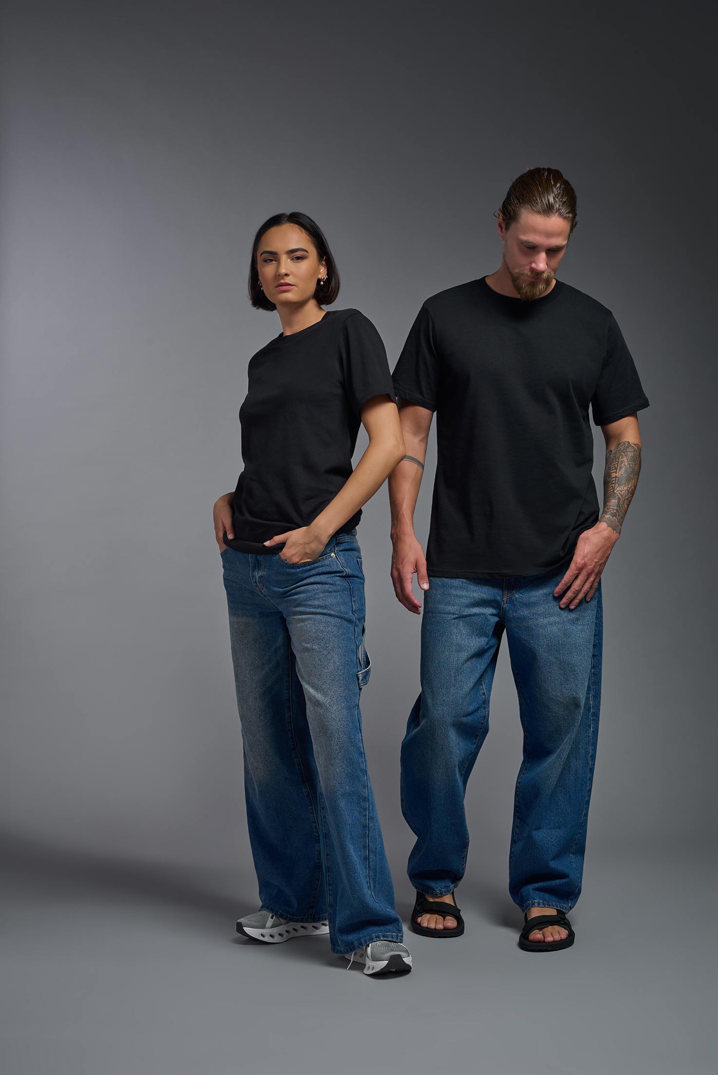 A male and female model wearing the unisex Organic Soft Cotton T-shirt in the color black, made in the USA from 100% GOTS certified organic cotton from a front view. #black