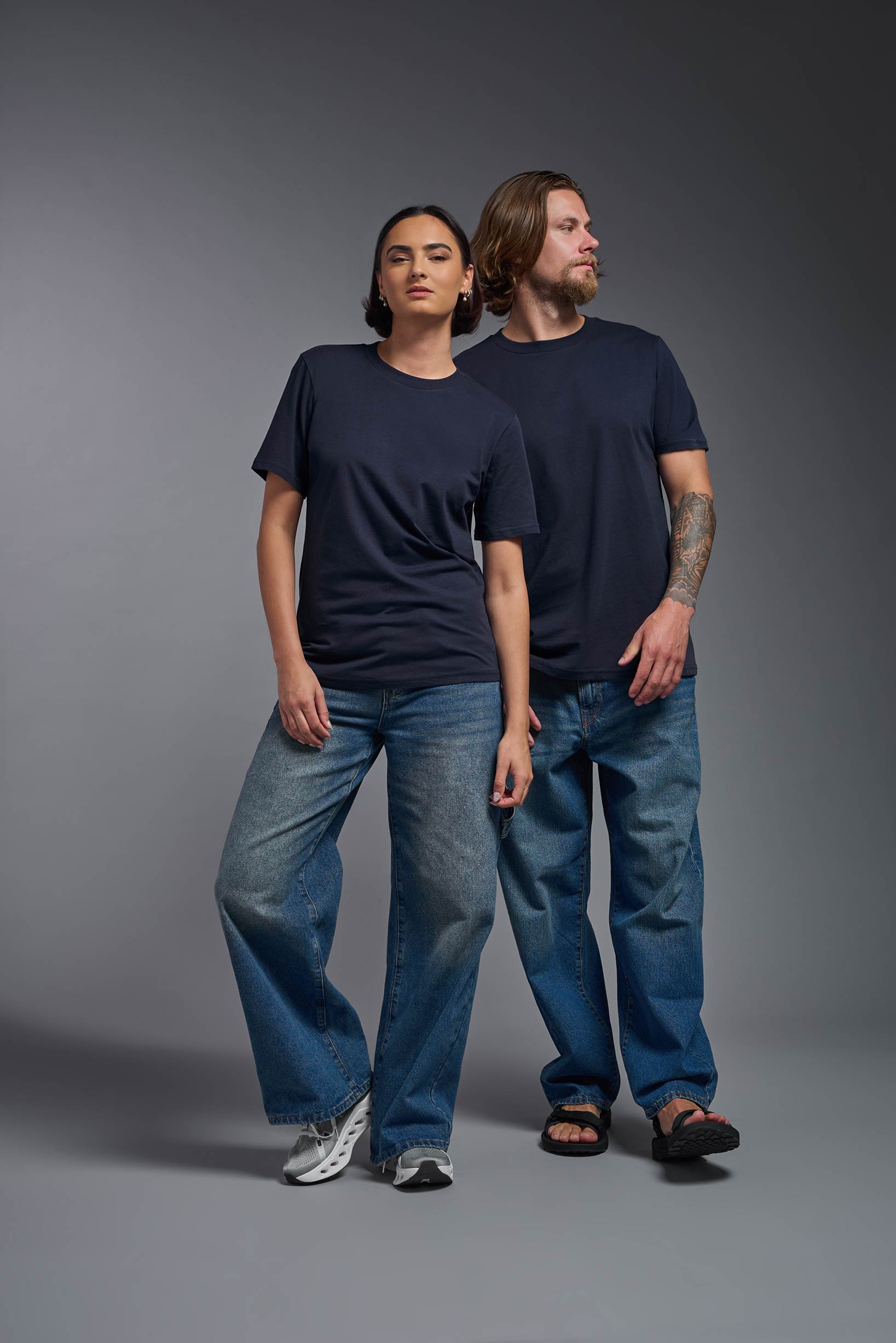 A male and female model wearing the unisex Organic Soft Cotton T-shirt in the color nova, made from 100% GOTS certified organic cotton from a full body side view. This shirt is unisex, made in the USA, and perfect for bulk screen printing and decorating. #nova