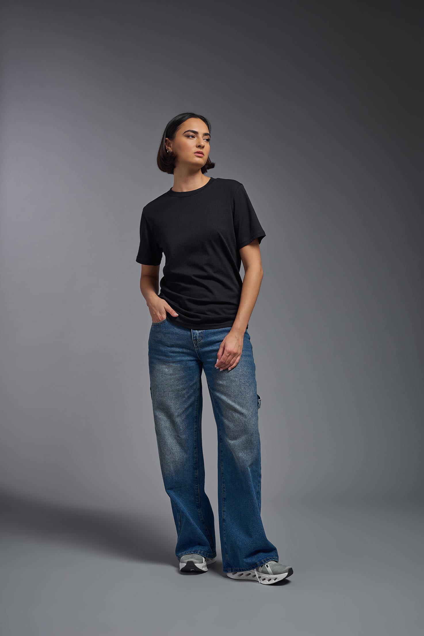 A female model wearing the unisex Organic Soft Cotton T-shirt in the color black, made in the USA from 100% GOTS certified organic cotton from a front view. This shirt is unisex, made in the USA, and perfect for bulk screen printing and decorating. #black