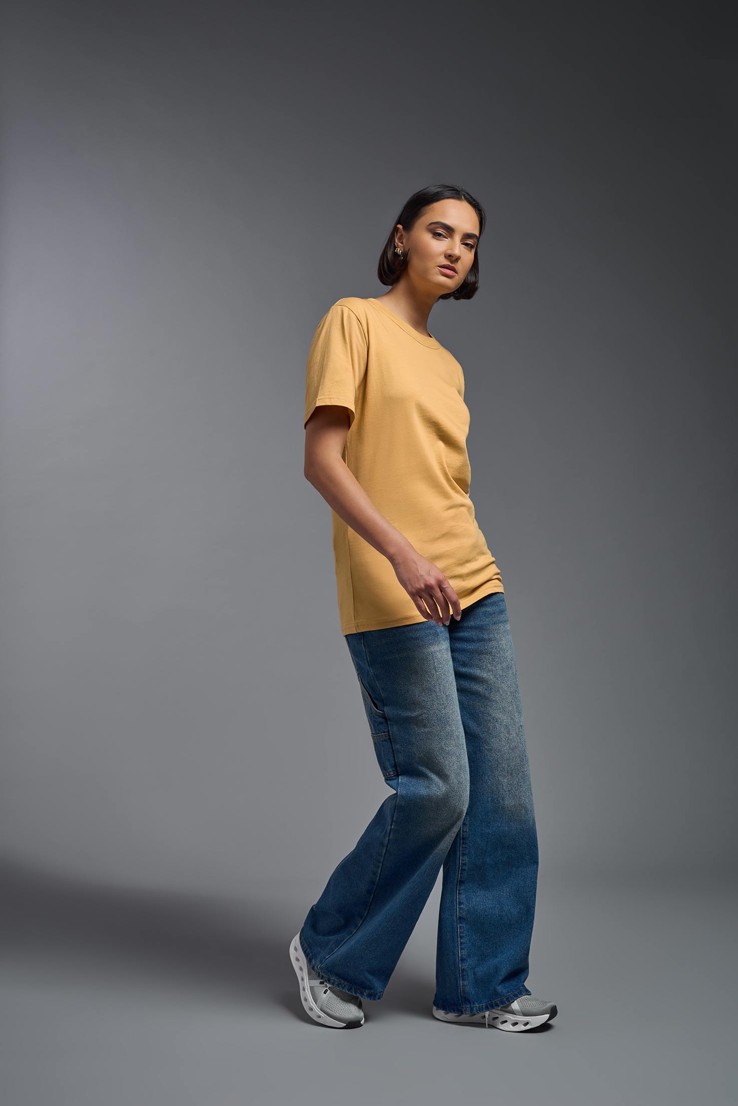 A female model wearing the unisex Organic Soft Cotton T-shirt in the color harvest, made in the USA from 100% GOTS certified organic cotton from a side view. This shirt is unisex, made in the USA, and perfect for bulk screen printing and decorating. #harvest