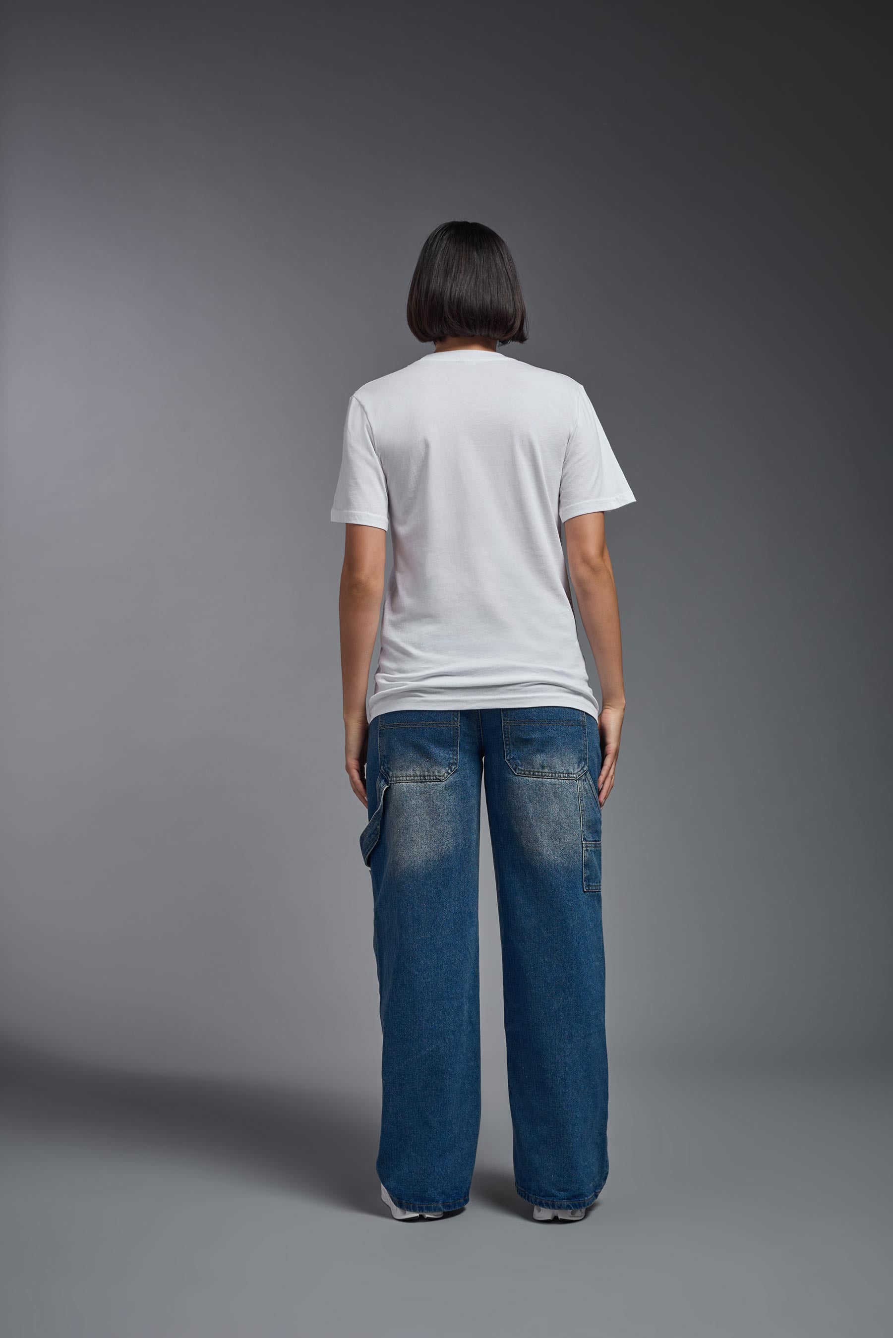 A female model wearing the unisex Organic Soft Cotton T-shirt in the color white, made in the USA from 100% GOTS certified organic cotton from back view. #white