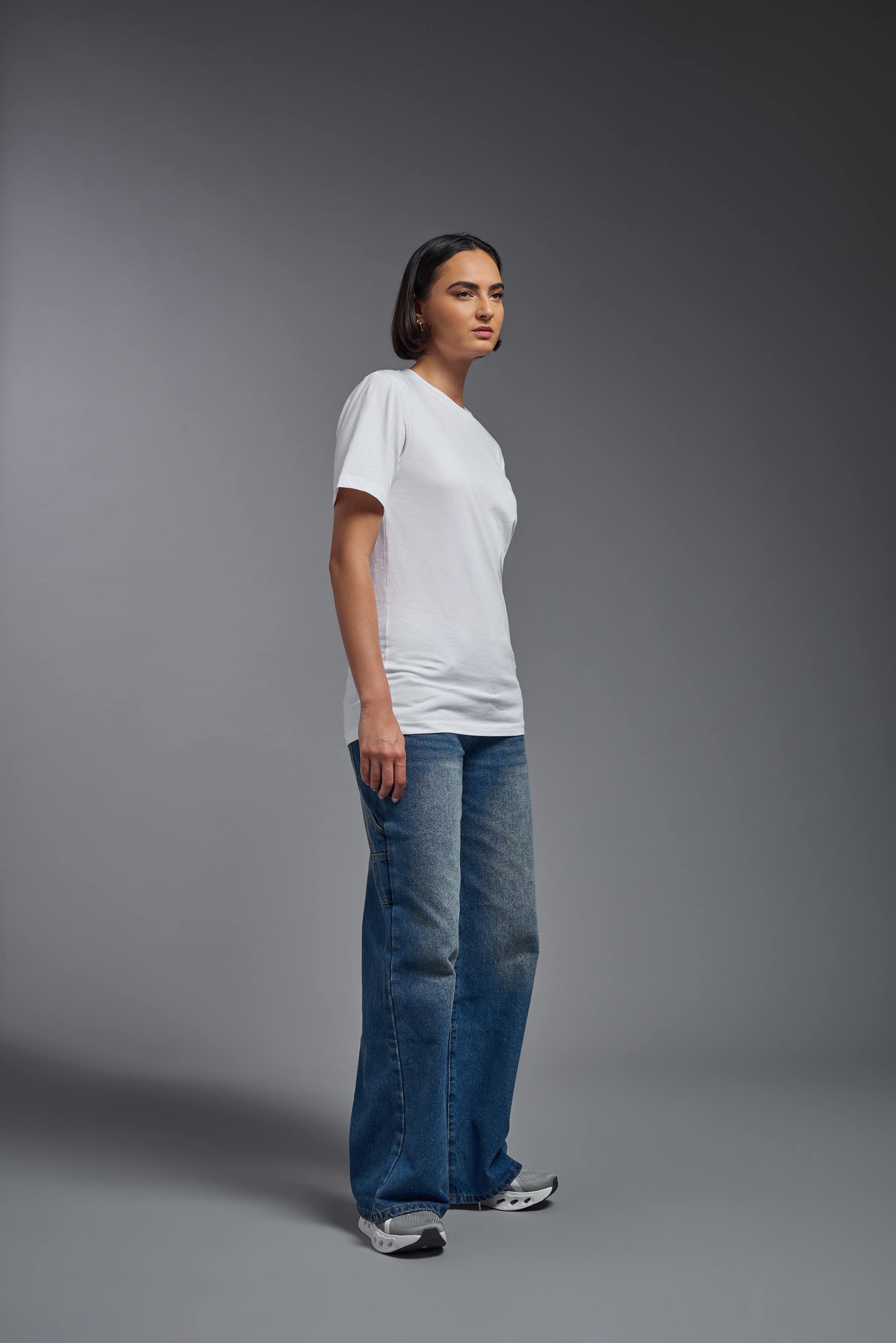 A female model wearing the unisex Organic Soft Cotton T-shirt in the color white, made in the USA from 100% GOTS certified organic cotton from side view. #white