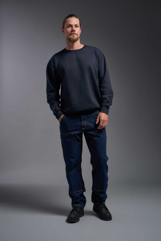 A male model wearing the unisex Americana 3-End Fleece Crewneck Sweatshirt in the color navy, made from 75% combed ring-spun USA-grown cotton and 25% polyester, showing the relaxed fit from a front view. This premium fleece hoodie is Made in the USA. #navy