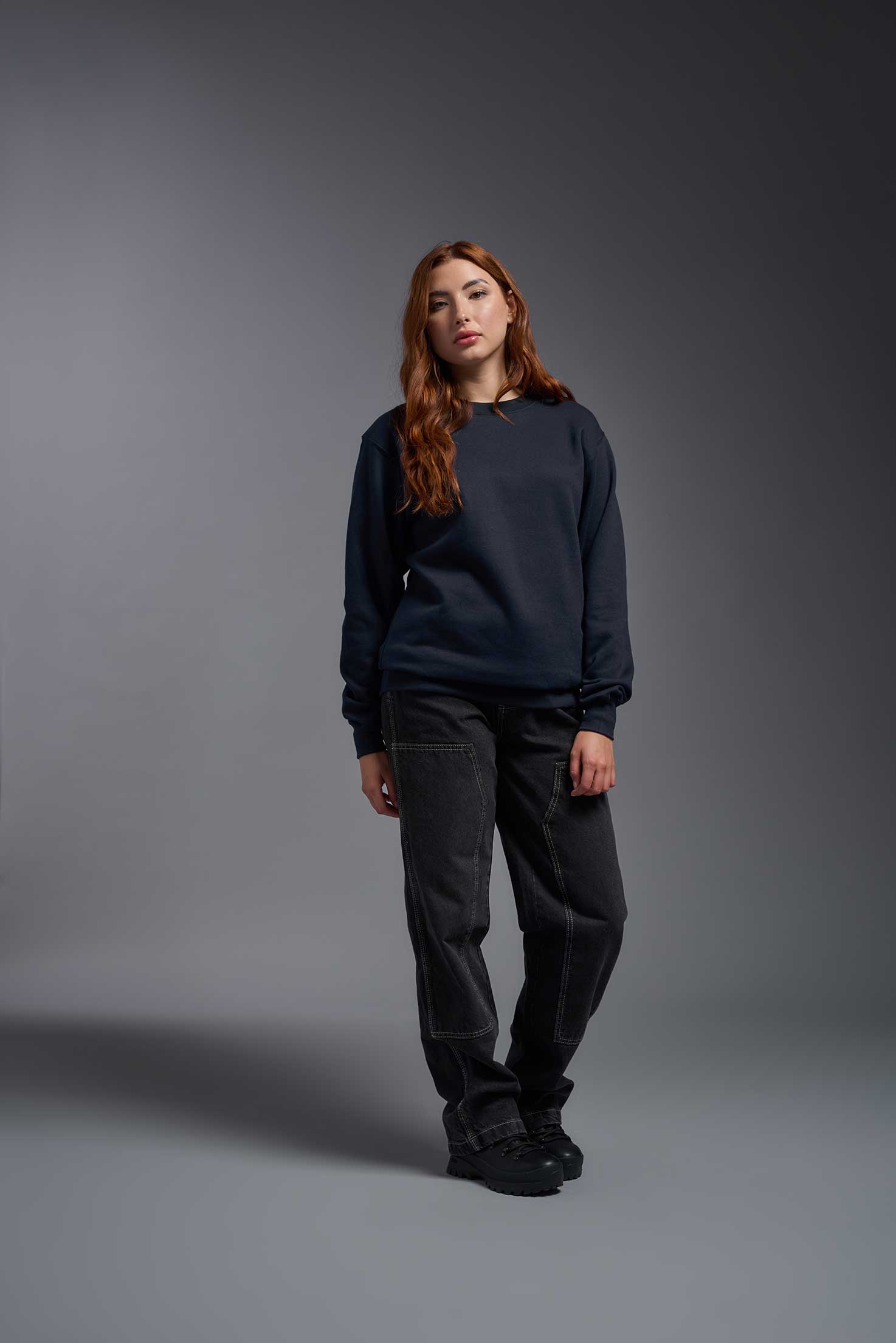 A female model wearing the unisex Americana 3-End Fleece Crewneck Sweatshirt in the color navy, made from 75% combed ring-spun USA-grown cotton and 25% polyester, showing the relaxed fit from a front view. This premium fleece hoodie is Made in the USA. #navy