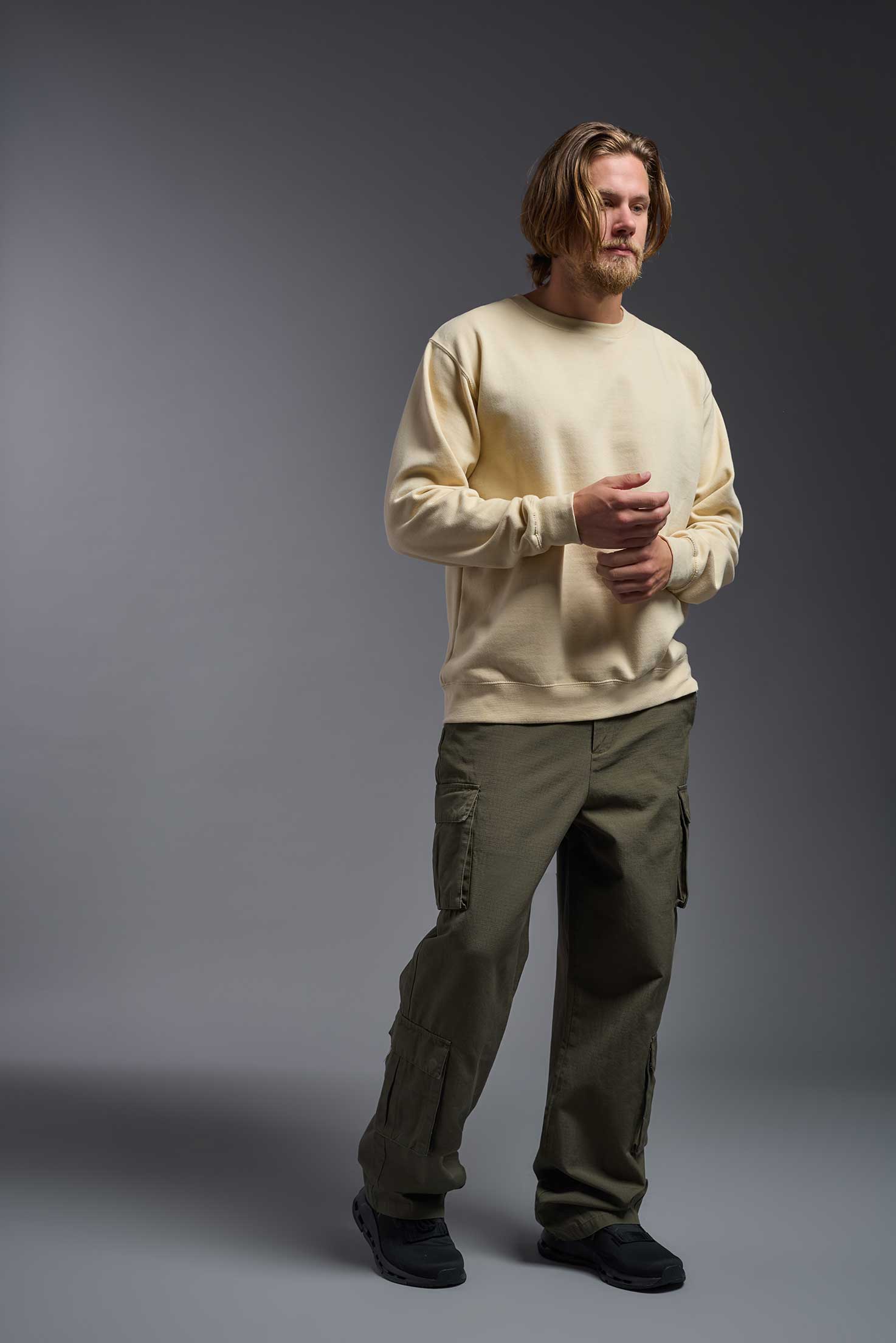 A male model wearing the unisex Americana 3-End Fleece Crewneck Sweatshirt in the color sand, made from 75% combed ring-spun USA-grown cotton and 25% polyester, showing the relaxed fit from a front view. This premium fleece hoodie is Made in the USA. #sand