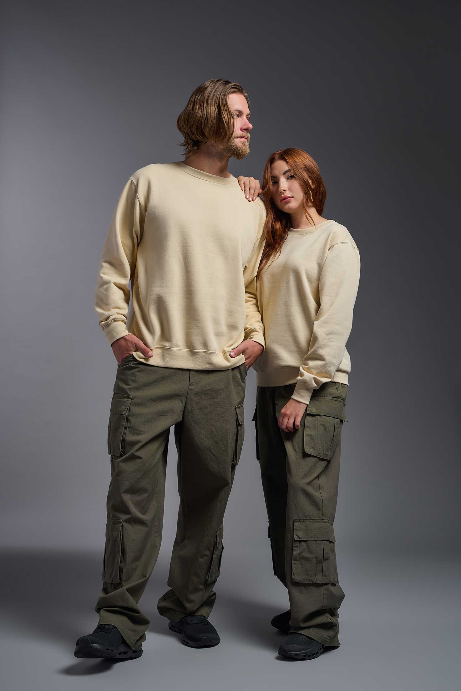 A male and female model wearing the unisex Americana 3-End Fleece Crewneck Sweatshirt in the color sand, made from 75% combed ring-spun USA-grown cotton and 25% polyester, showing the relaxed fit from a front view. This premium fleece hoodie is Made in the USA. #sand