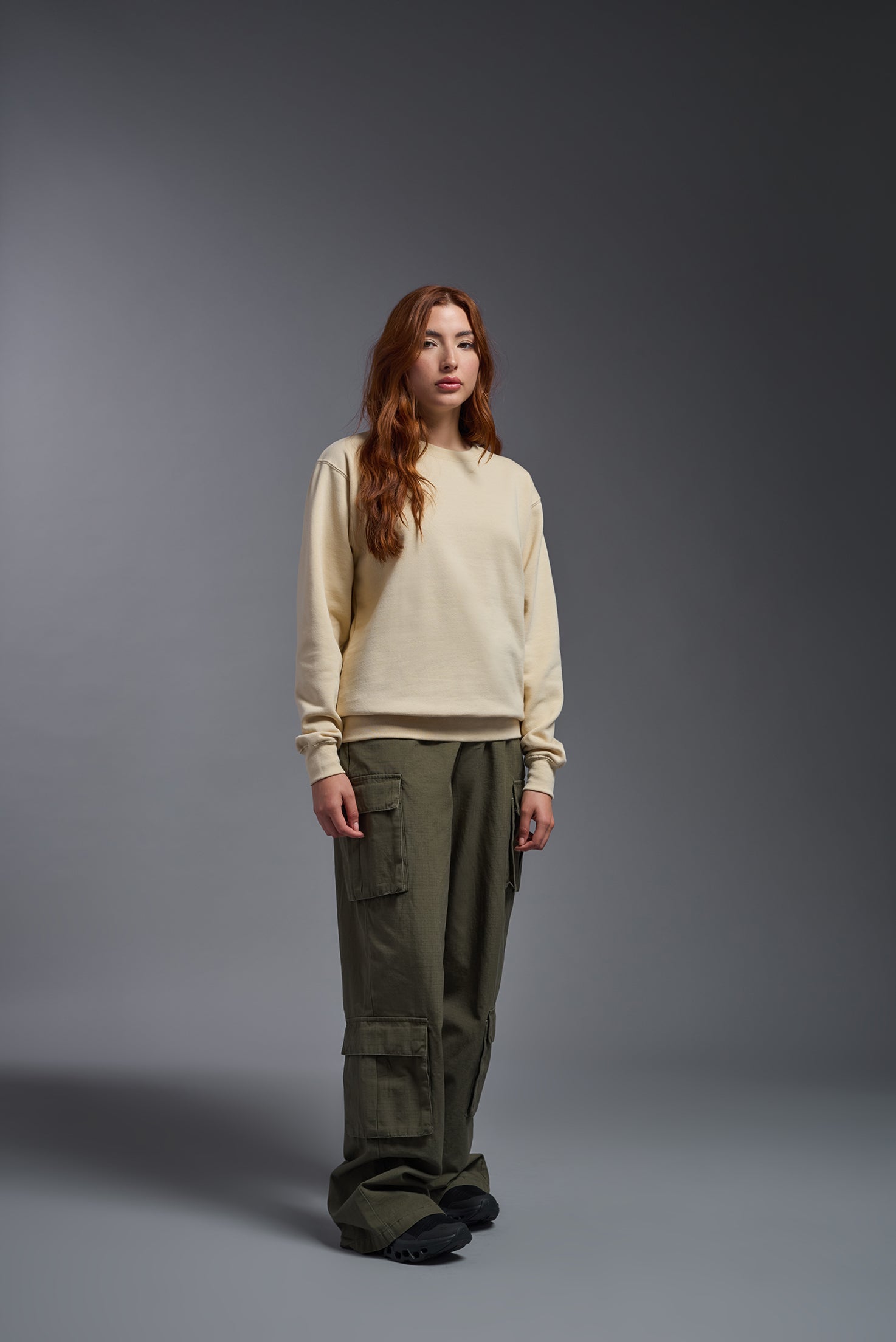 A female model wearing the unisex Americana 3-End Fleece Crewneck Sweatshirt in the color sand, made from 75% combed ring-spun USA-grown cotton and 25% polyester, showing the relaxed fit from a front view. This premium fleece hoodie is Made in the USA. #sand