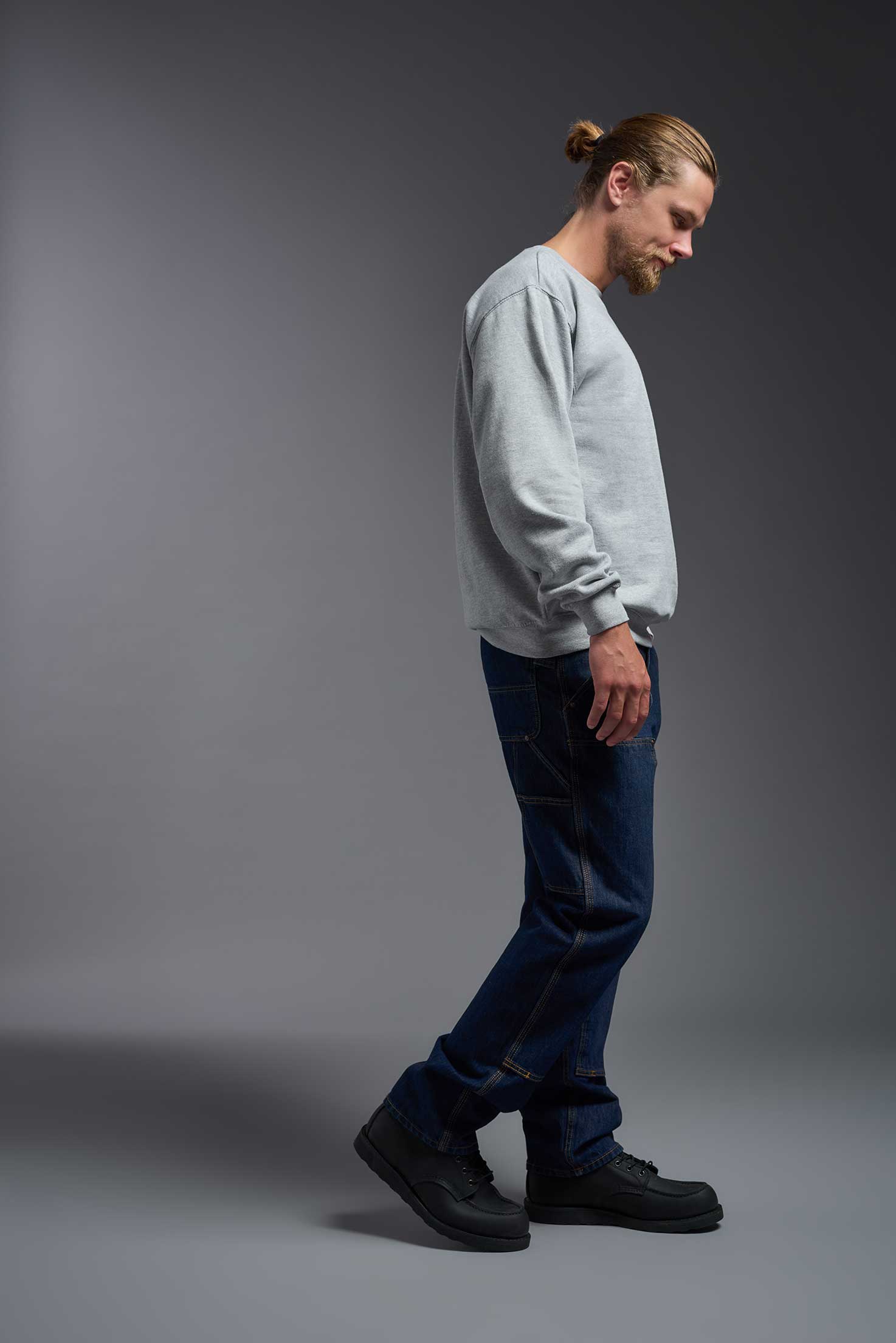 A male model wearing the unisex Americana 3-End Fleece Crewneck Sweatshirt in the color sport gray, made from 75% combed ring-spun USA-grown cotton and 25% polyester, showing the relaxed fit from a side view. This premium fleece hoodie is Made in the USA. #sport-gray