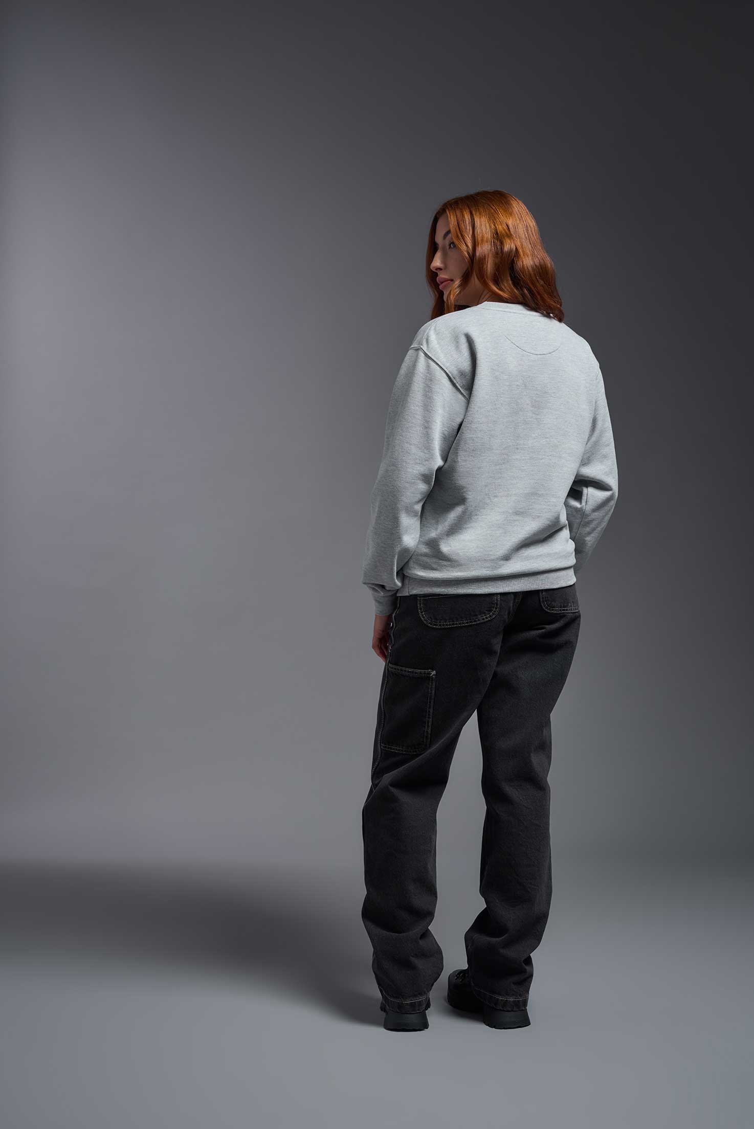 A female model wearing the unisex Americana 3-End Fleece Crewneck Sweatshirt in the color sport gray, made from 75% combed ring-spun USA-grown cotton and 25% polyester, showing the relaxed fit from a back view. This premium fleece hoodie is Made in the USA. #sport-gray
