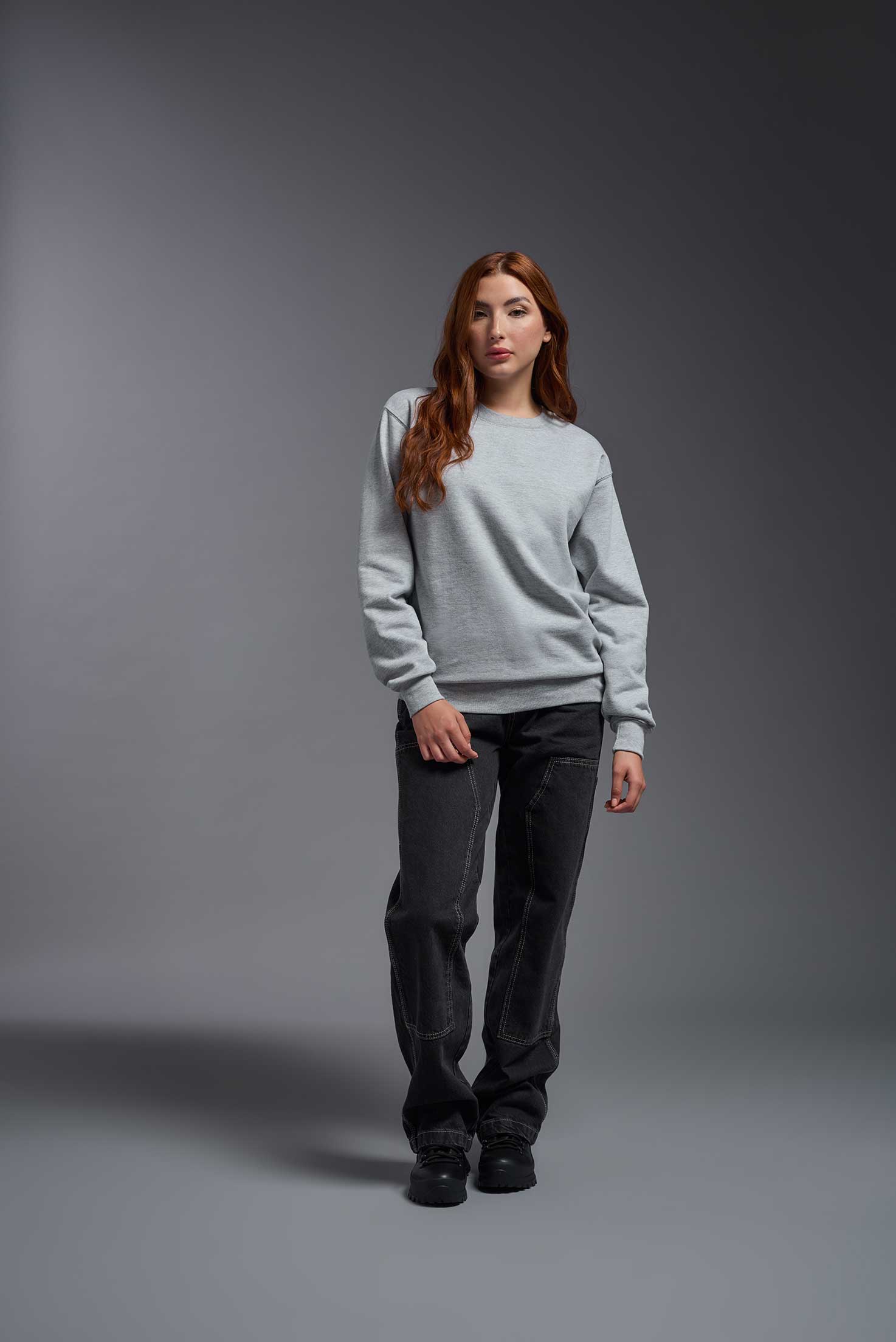 A female model wearing the unisex Americana 3-End Fleece Crewneck Sweatshirt in the color sport gray, made from 75% combed ring-spun USA-grown cotton and 25% polyester, showing the relaxed fit from a front view. This premium fleece hoodie is Made in the USA. #sport-gray