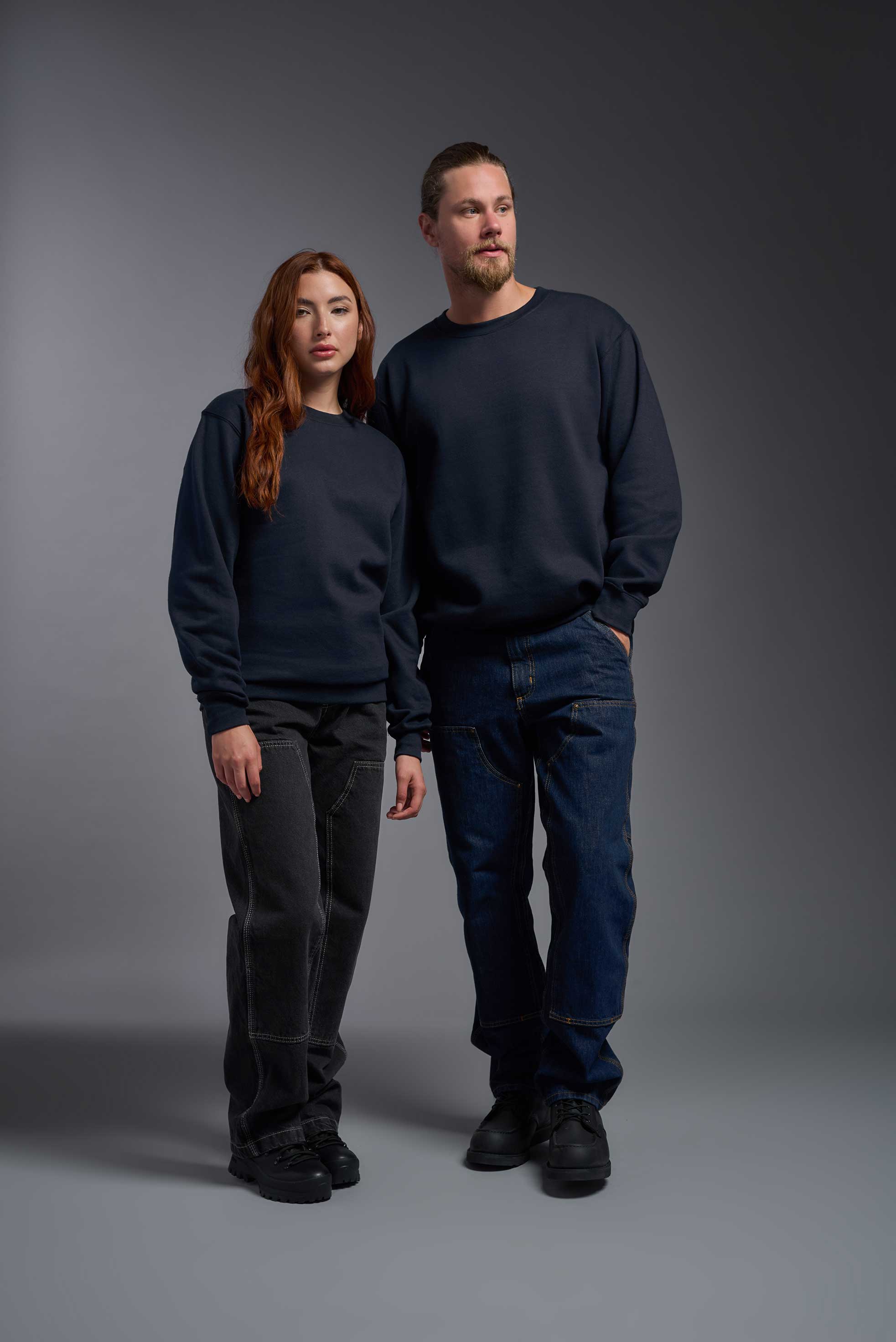 A male and female model wearing the unisex Americana 3-End Fleece Crewneck Sweatshirt in the color navy, made from 75% combed ring-spun USA-grown cotton and 25% polyester, showing the relaxed fit from a front view. This premium fleece hoodie is Made in the USA. #navy