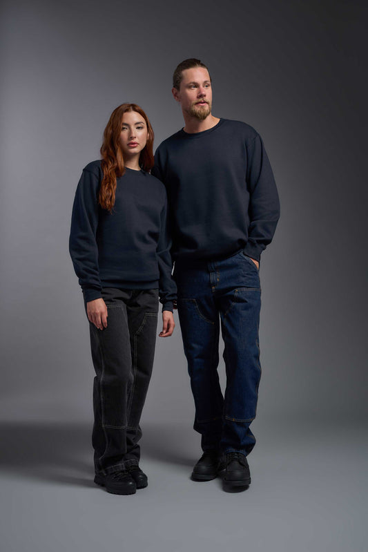 A male and female model wearing the unisex Americana 3-End Fleece Crewneck Sweatshirt in the color navy, made from 75% combed ring-spun USA-grown cotton and 25% polyester, showing the relaxed fit from a front view. This premium fleece hoodie is Made in the USA. #navy