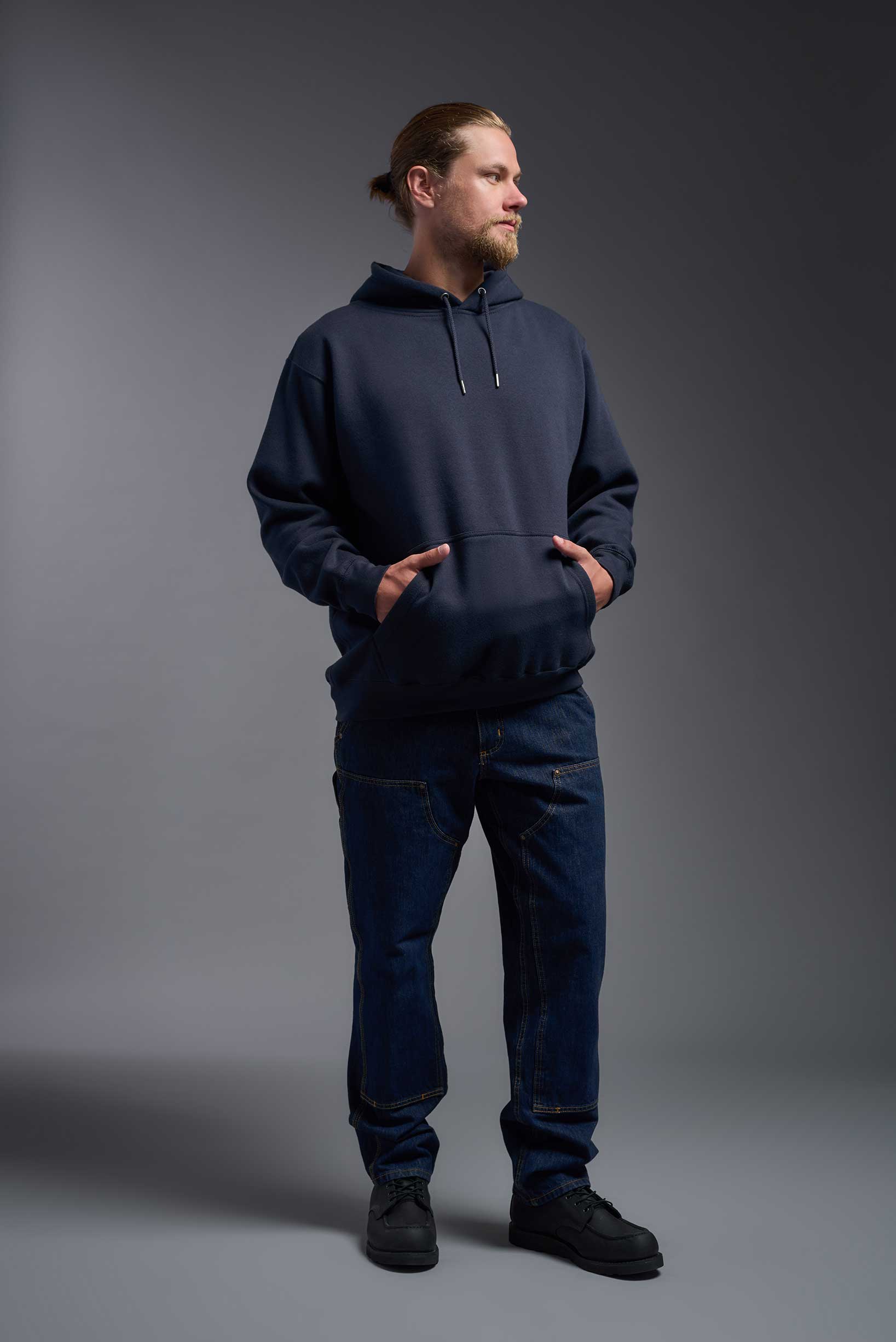 A male model wearing the unisex Americana 3-End Fleece Pullover Hoodie in the color navy, made from 75% combed ring-spun USA-grown cotton and 25% polyester, showing the relaxed fit from a front view. This premium fleece hoodie is Made in the USA. #navy
