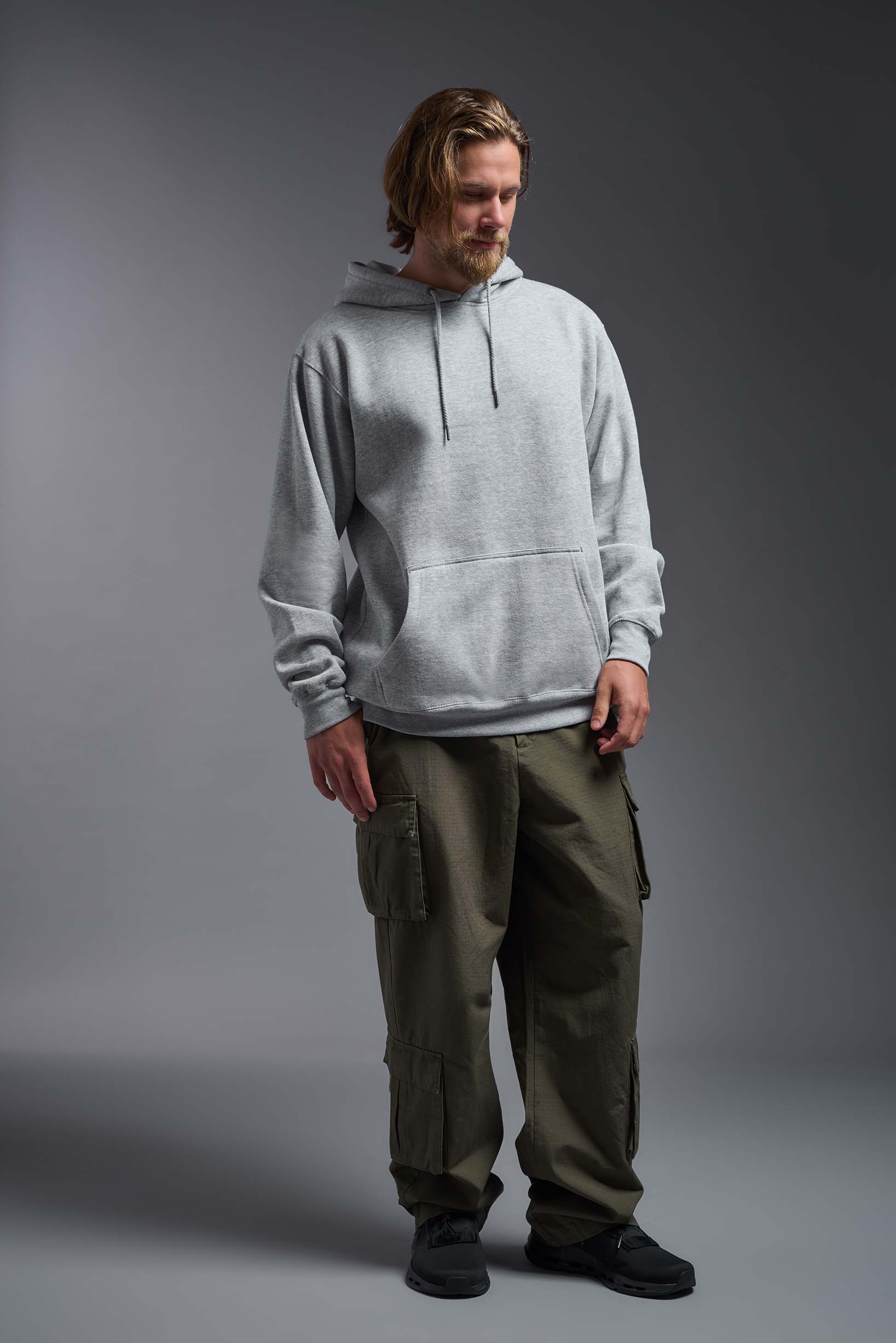 A male model wearing the unisex Americana 3-End Fleece Pullover Hoodie in the color sport gray, made from 75% combed ring-spun USA-grown cotton and 25% polyester, showing the relaxed fit from a front view. This premium fleece hoodie is Made in the USA. #sport-gray
