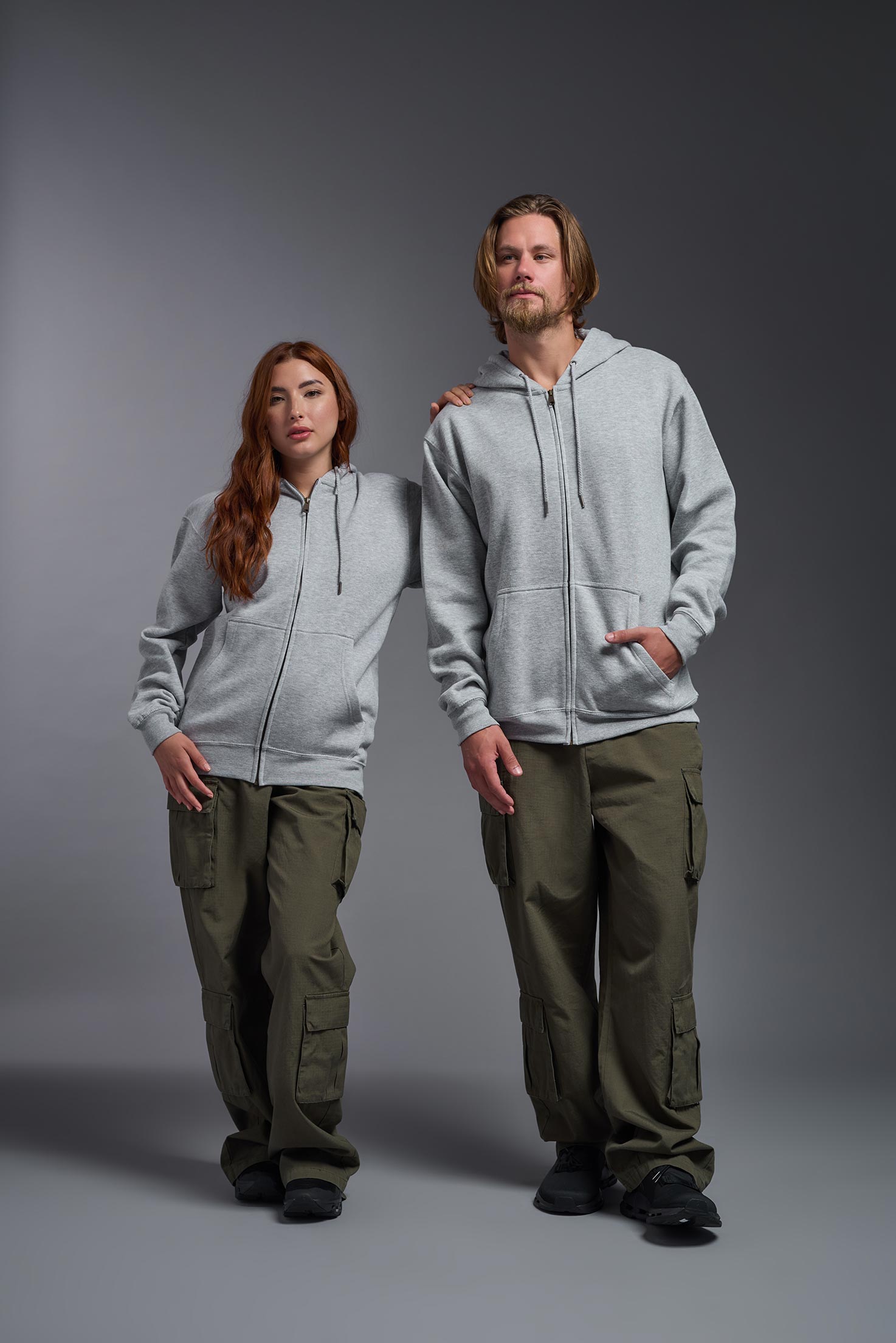 A male  and female model wearing the unisex Americana 3-End Fleece Full Zip Hoodie in the color sport gray, made from 75% combed ring-spun USA-grown cotton and 25% polyester, showing the relaxed fit from a front view. This premium fleece hoodie is Made in the USA. #sport-gray