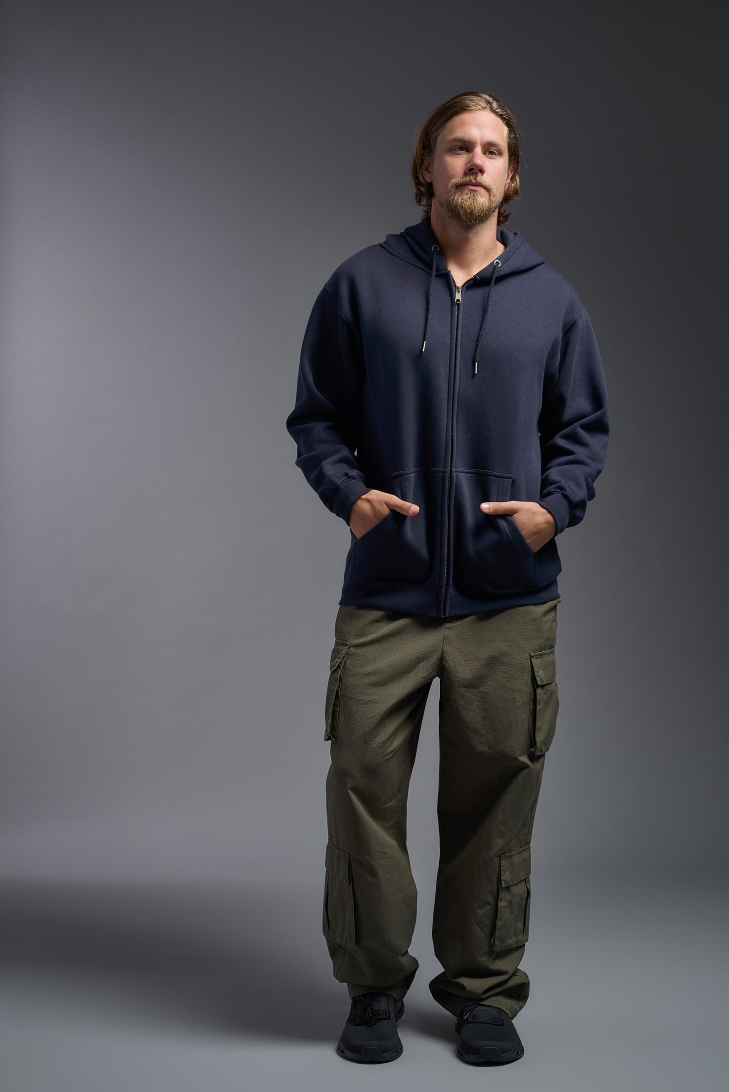 A male model wearing the unisex Americana 3-End Fleece Full Zip Hoodie in the color navy, made from 75% combed ring-spun USA-grown cotton and 25% polyester, showing the relaxed fit from a front view. This premium fleece hoodie is Made in the USA. #navy