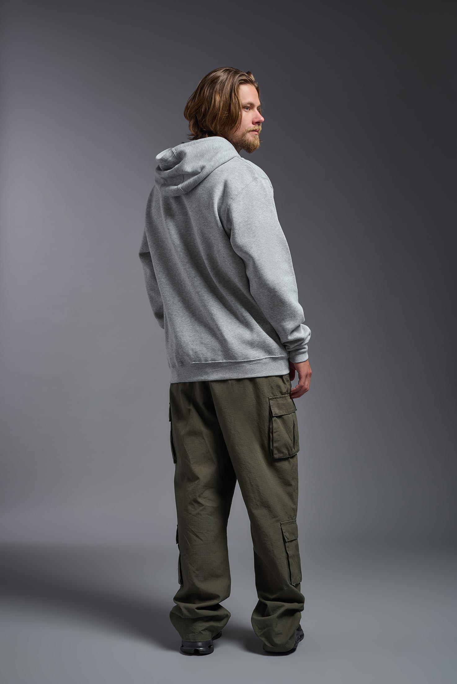 A male model wearing the unisex Americana 3-End Fleece Full Zip Hoodie in the color sport gray, made from 75% combed ring-spun USA-grown cotton and 25% polyester, showing the relaxed fit from a back view. This premium fleece hoodie is Made in the USA. #sport-gray