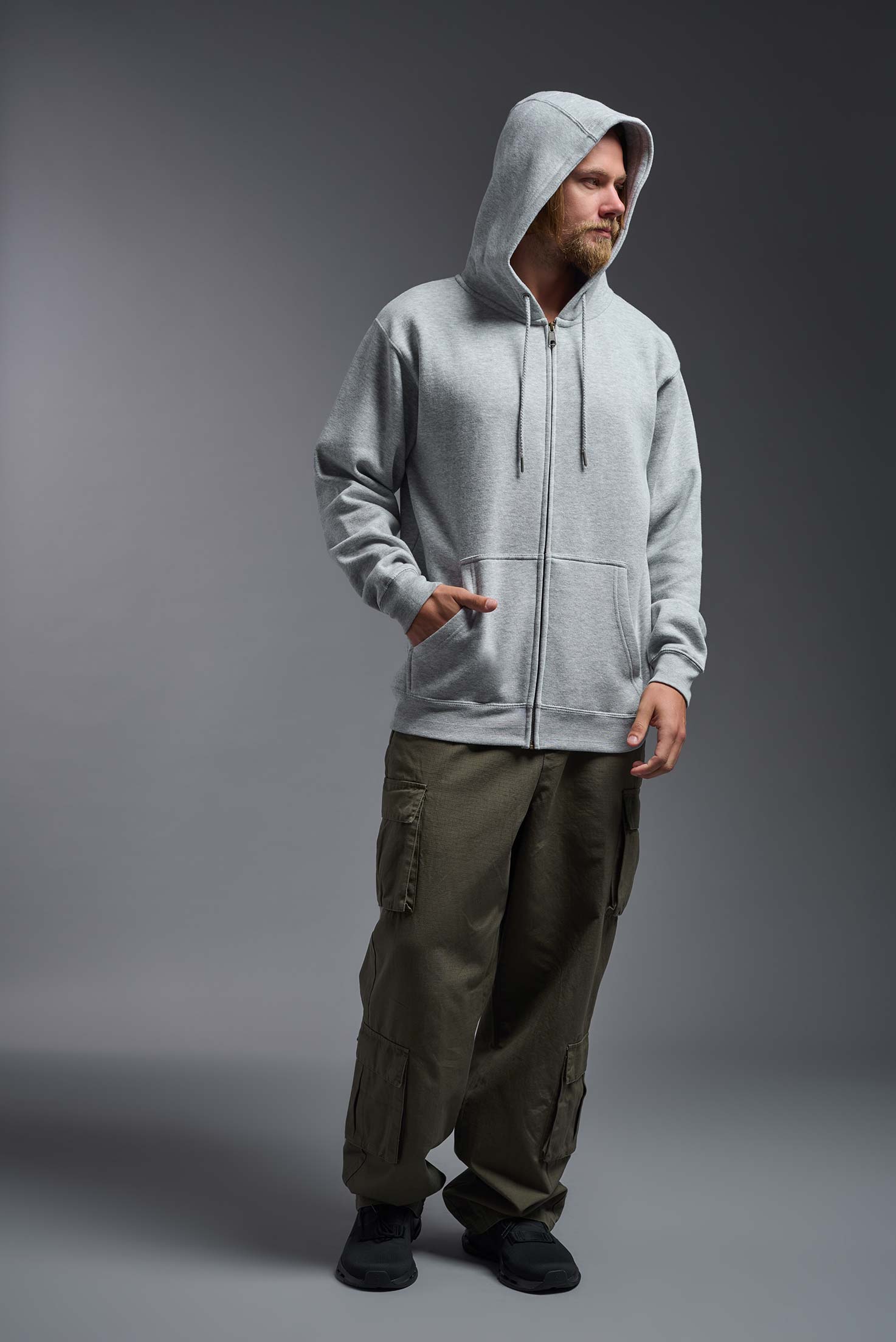 A male model wearing the unisex Americana 3-End Fleece Full Zip Hoodie in the color sport gray, made from 75% combed ring-spun USA-grown cotton and 25% polyester, showing the relaxed fit from a front view with hood up. This premium fleece hoodie is Made in the USA. #sport-gray