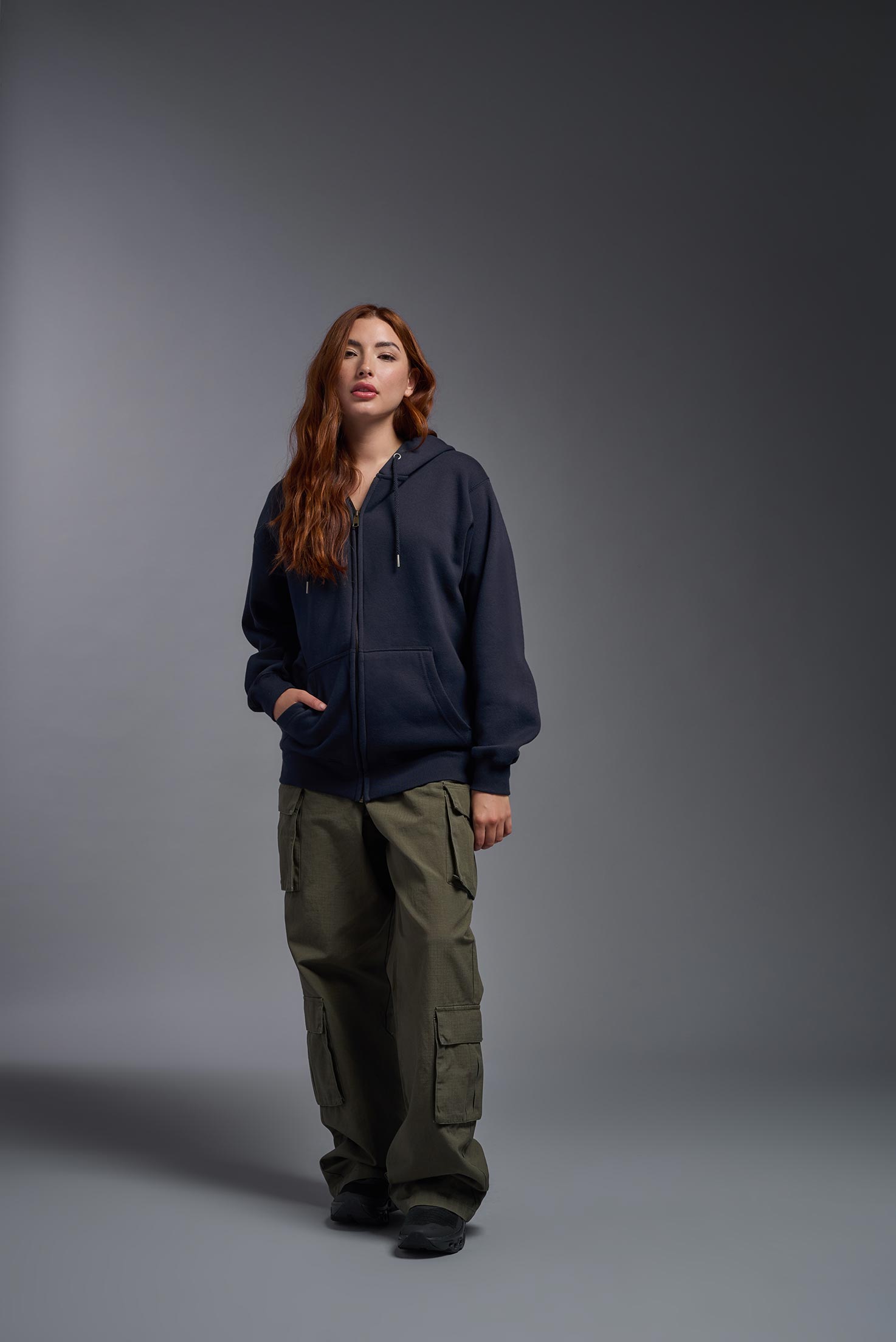 A female model wearing the unisex Americana 3-End Fleece Full Zip Hoodie in the color navy, made from 75% combed ring-spun USA-grown cotton and 25% polyester, showing the relaxed fit from a front view. This premium fleece hoodie is Made in the USA. #navy
