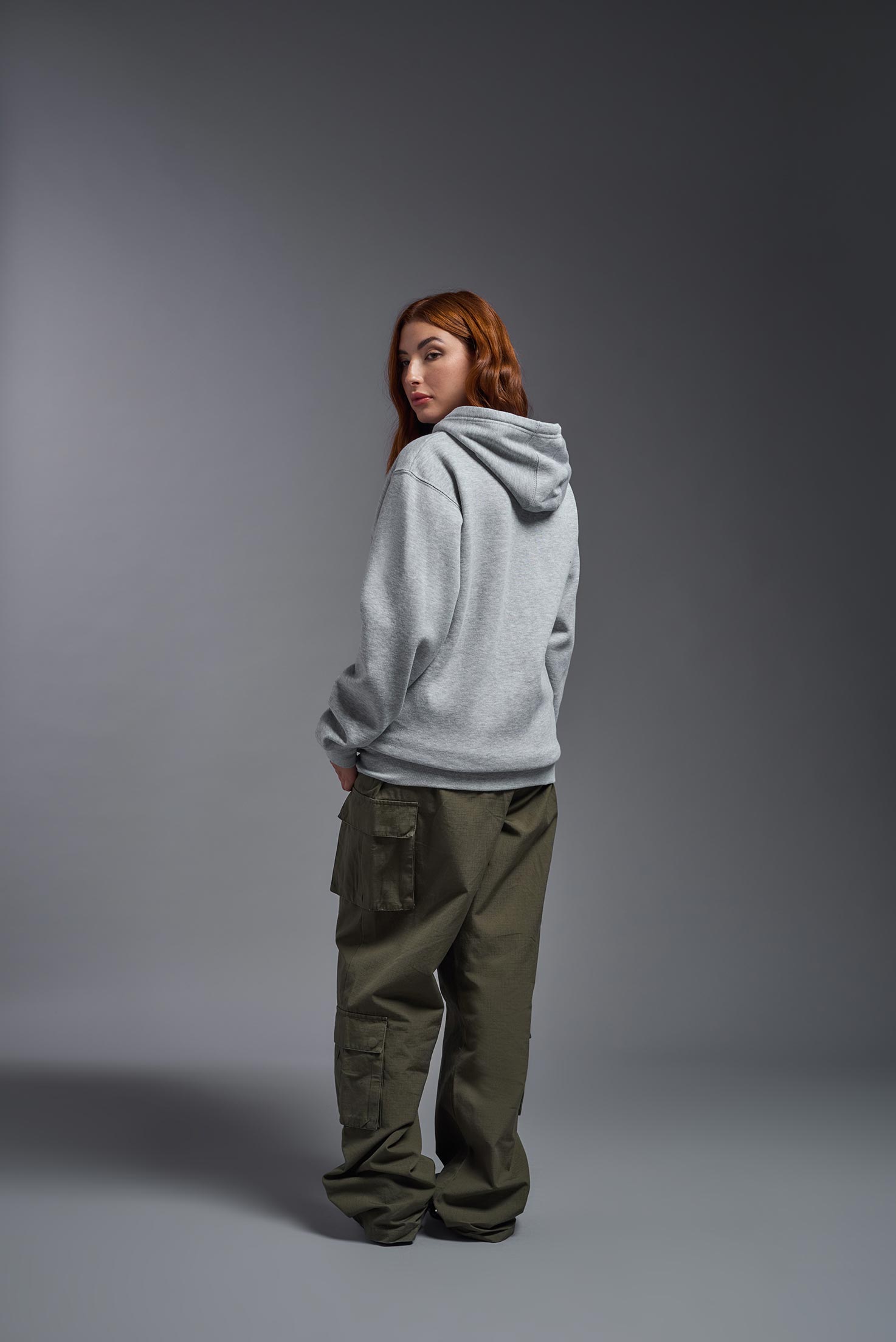 A female model wearing the unisex Americana 3-End Fleece Full Zip Hoodie in the color sport gray, made from 75% combed ring-spun USA-grown cotton and 25% polyester, showing the relaxed fit from a back view. This premium fleece hoodie is Made in the USA. #sport-gray