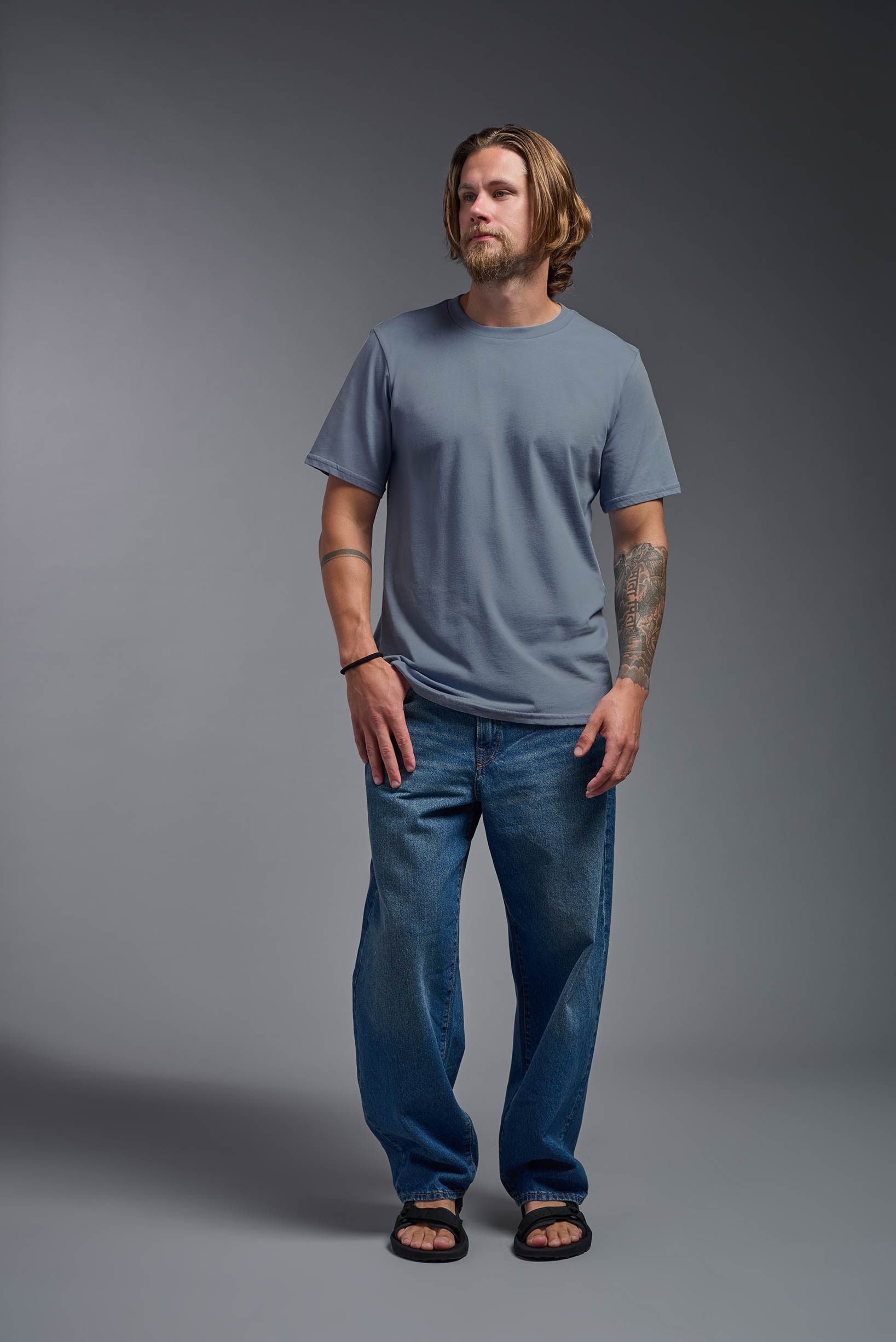 A male model wearing the unisex Organic Soft Cotton T-shirt in the color canyon blue, made in the USA from 100% GOTS certified organic cotton from a front view. This shirt is unisex, made in the USA, and perfect for bulk screen printing and decorating. #canyon-blue