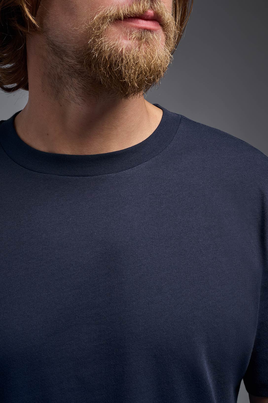 A male model wearing the unisex Organic Soft Cotton T-shirt in the color nova, made from 100% GOTS certified organic cotton from a closeup collar view. This shirt is unisex, made in the USA, and perfect for bulk screen printing and decorating. #nova