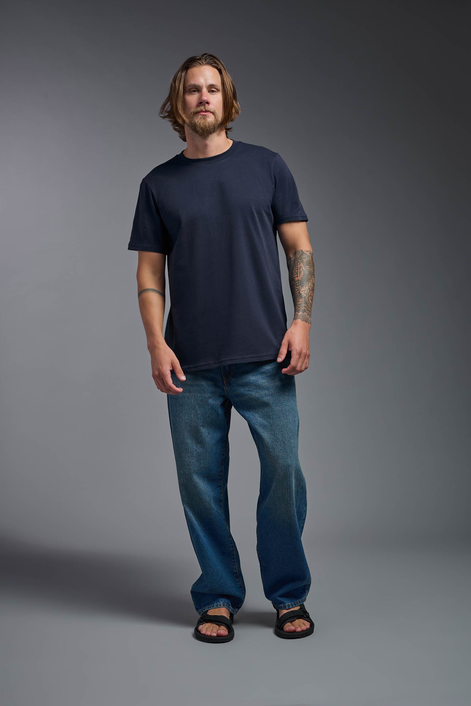 A male model wearing the unisex Organic Soft Cotton T-shirt in the color nova, made from 100% GOTS certified organic cotton from a full body front view. This shirt is unisex, made in the USA, and perfect for bulk screen printing and decorating. #nova