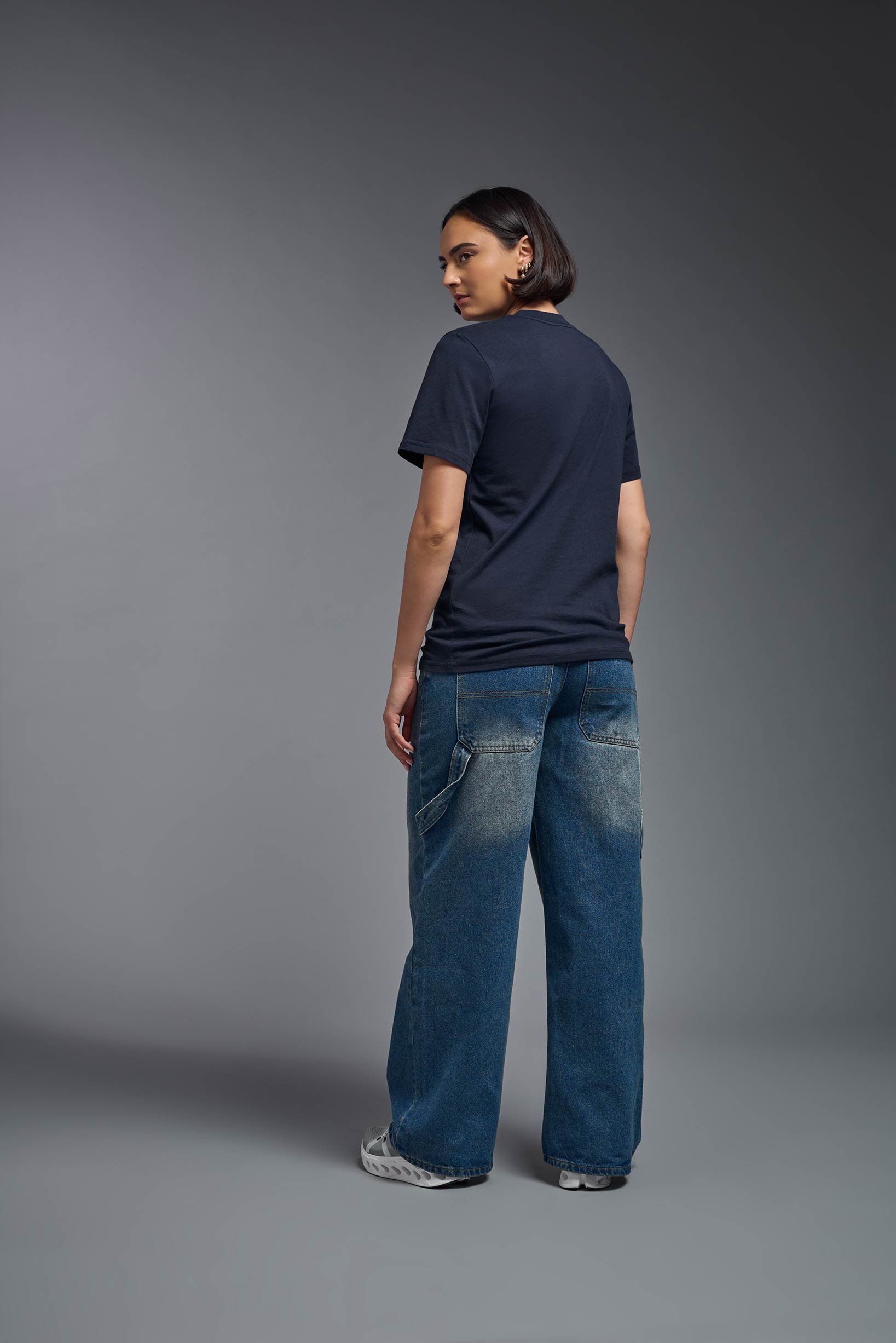 A female model wearing the unisex Organic Soft Cotton T-shirt in the color nova, made from 100% GOTS certified organic cotton from a full body back view. This shirt is unisex, made in the USA, and perfect for bulk screen printing and decorating. #nova