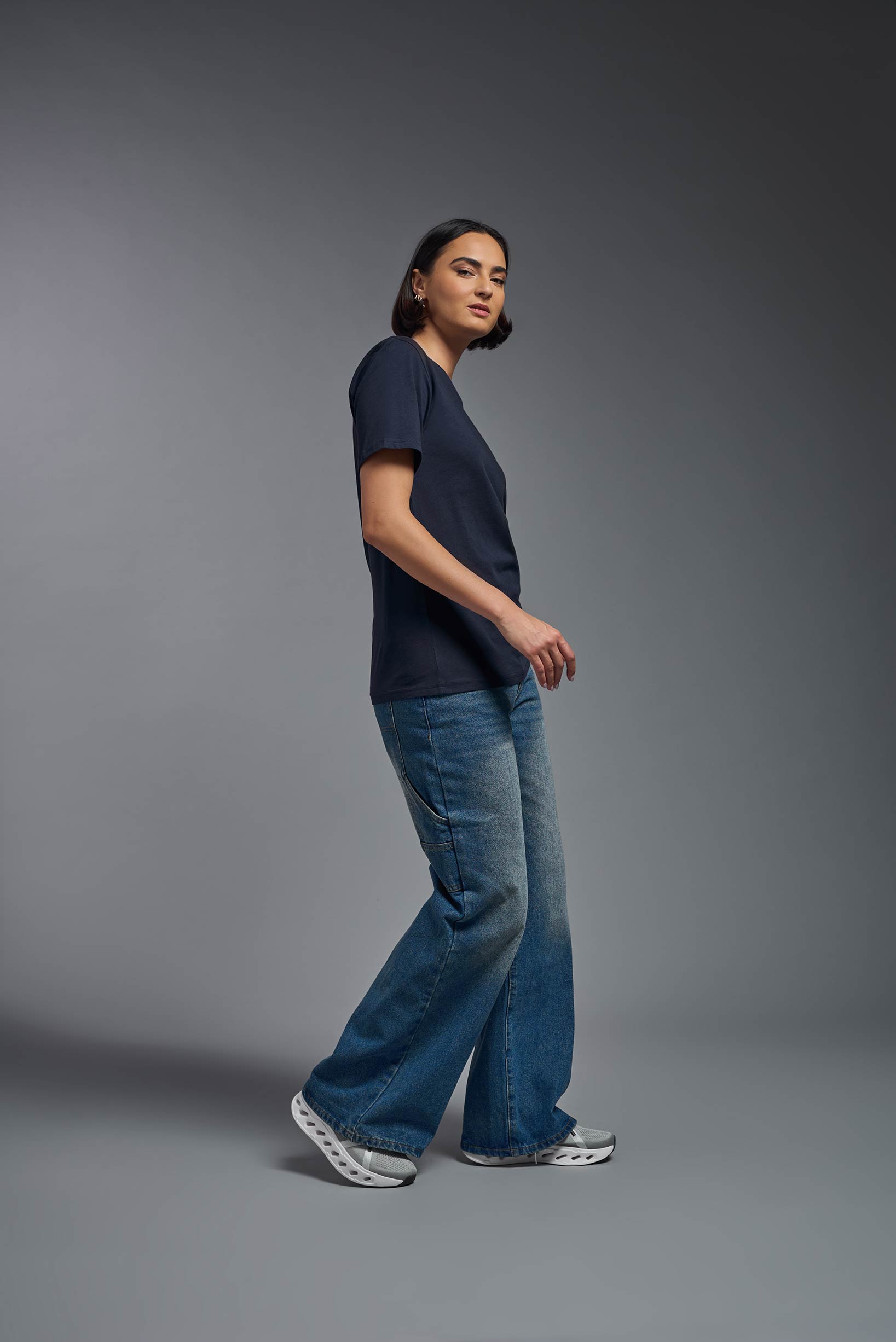 A female model wearing the unisex Organic Soft Cotton T-shirt in the color nova, made from 100% GOTS certified organic cotton from a full body side view. This shirt is unisex, made in the USA, and perfect for bulk screen printing and decorating. #nova