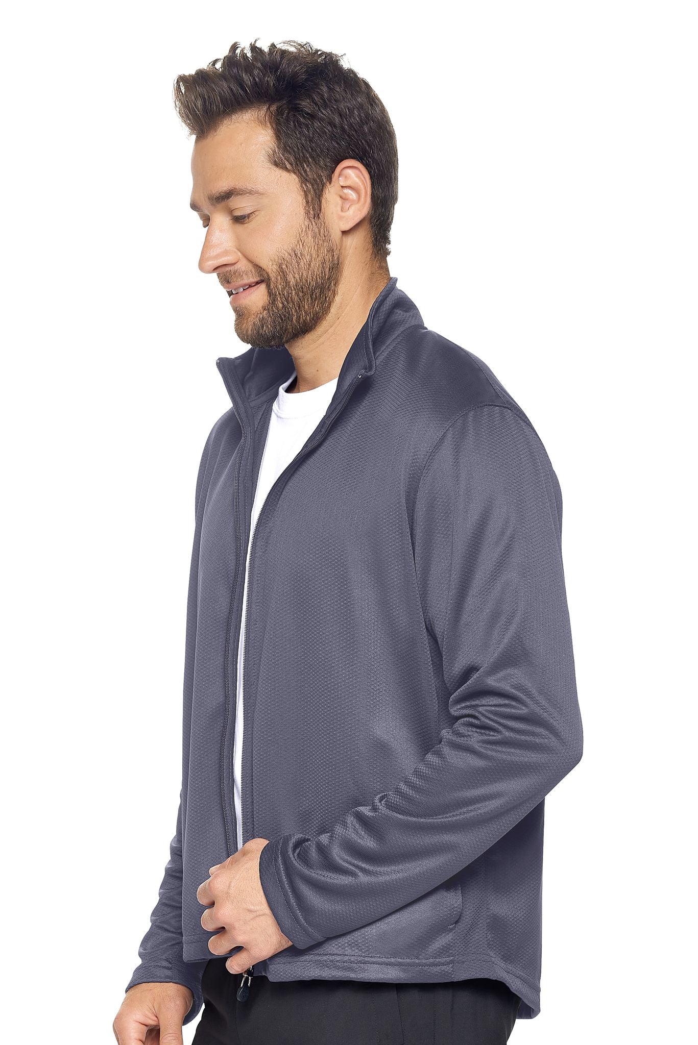 A male model on a white background wearing the men's Sphere Sportsman Jacket in the color charcoal made out of 100% polyester showing the relaxed fit from a side view. This jacket quick-dries, wicks moisture and is made in the USA. #charcoal