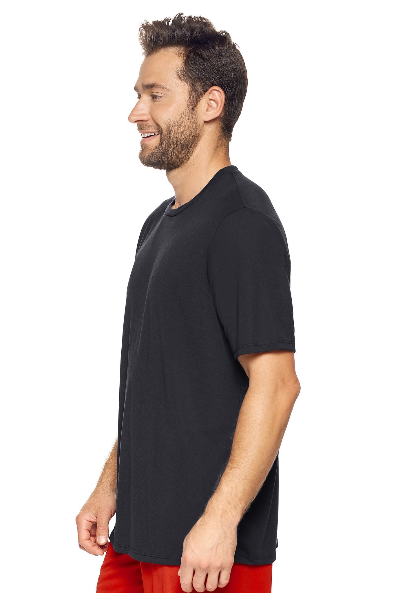 A male model with brown hair wearing the men's Siro™ Crewneck Tee in the color black, made from 100% filament polyester technology, showing the modern fit from a side view. This shirt is elevated and fashion forward while also offering quick-drying and moisture-wicking performance. It is made in the USA, and available for bulk purchase. #black
