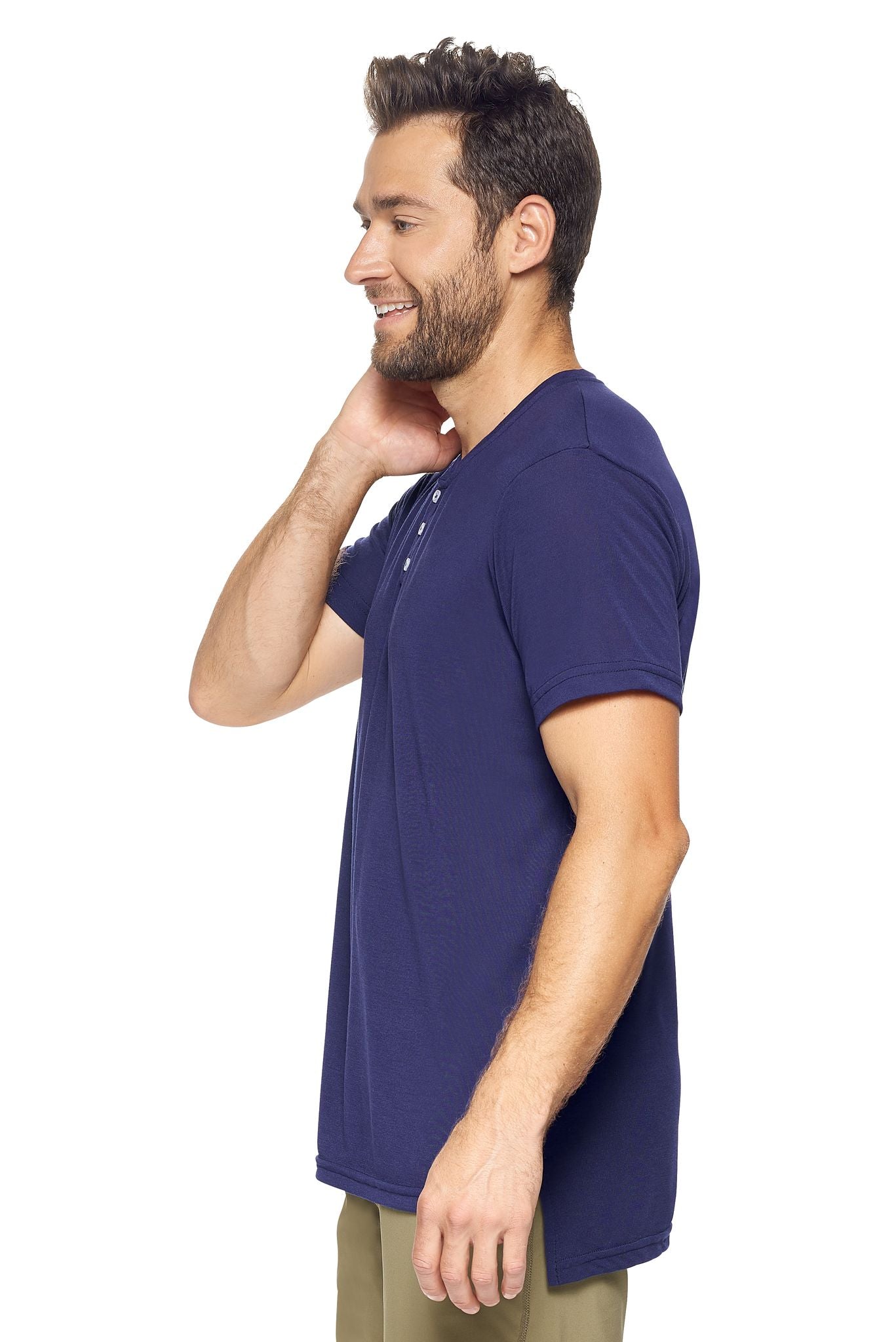 A male model with brown hair on a white background wearing the men's Siro™ Drop Tail Henley in the color navy, made out of 100% polyester, showing the relaxed fit from a side view. This 3-button shirt features snag-free filament technology, is super soft, breathable, quick-drying, moisture-wicking, and made in the USA. #navy