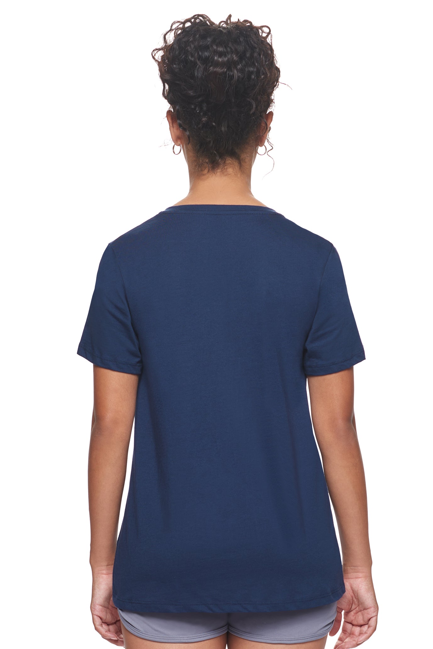 A female model with curly hair wearing the Women's MoCA V-Neck Tee in the color navy, made from a luxurious blend of 50% LENZING Modal and 50% Combed Ring-Spun Cotton, showing the relaxed feminine fit from a back view. This fashion-forward, more sustainable t-shirt is elevated, eco-friendly, made in the USA, and available for bulk purchase. #navy