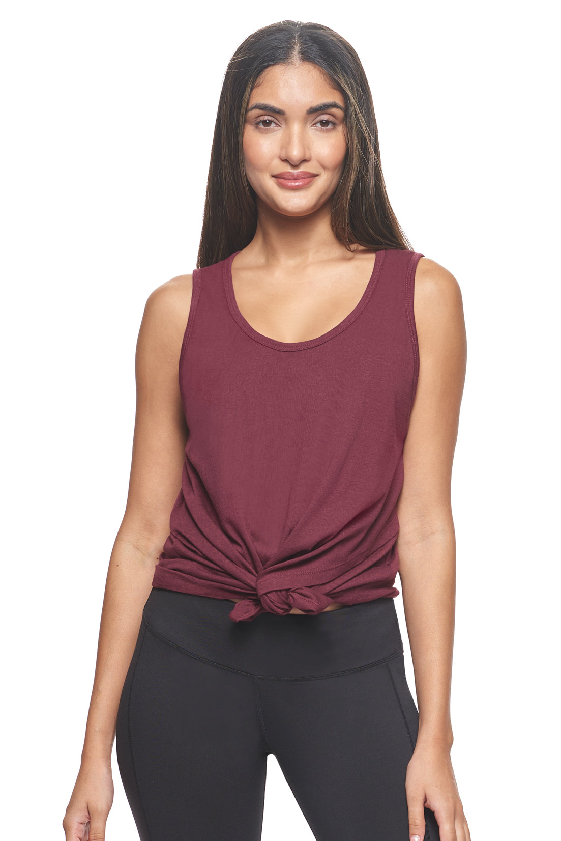 A female model with brown hair wearing the women's MoCA Tie Front Tank Tee in the color maroon, made from a luxurious blend of 50% LENZING Modal and 50% Combed Ring-Spun Cotton, showing the relaxed fit from a front tied view. This fashion-forward, more sustainable t-shirt is elevated, eco-friendly, made in the USA, and available for bulk purchase. #maroon