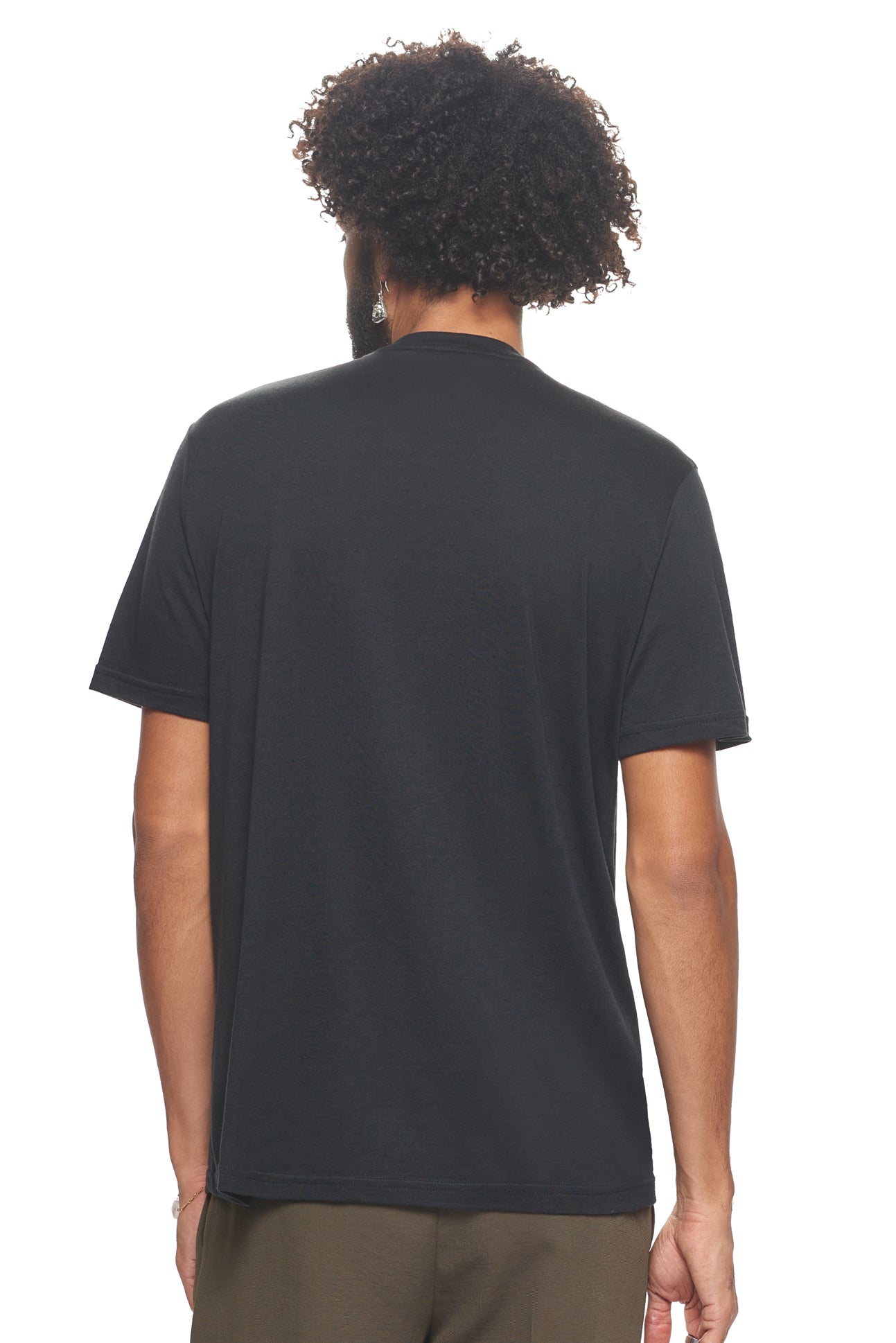 A male model with curly hair wearing the Men's MoCA V-Neck Tee in the color black, made from a luxurious blend of 50% LENZING Modal and 50% Combed Ring-Spun Cotton, showing the relaxed fit from a back view. This fashion-forward, more sustainable t-shirt is elevated, eco-friendly, made in the USA, and available for bulk purchase. #black