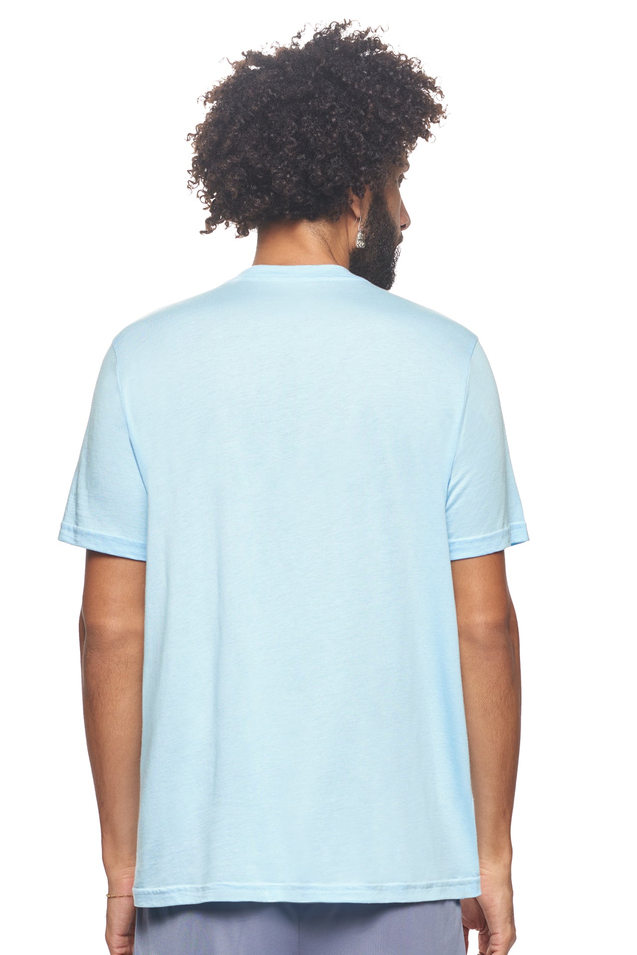 A male model with curly hair wearing the Men's MoCA V-Neck Tee in the color light blue, made from a luxurious blend of 50% LENZING Modal and 50% Combed Ring-Spun Cotton, showing the relaxed fit from a back view. This fashion-forward, more sustainable t-shirt is elevated, eco-friendly, made in the USA, and available for bulk purchase. #light-blue