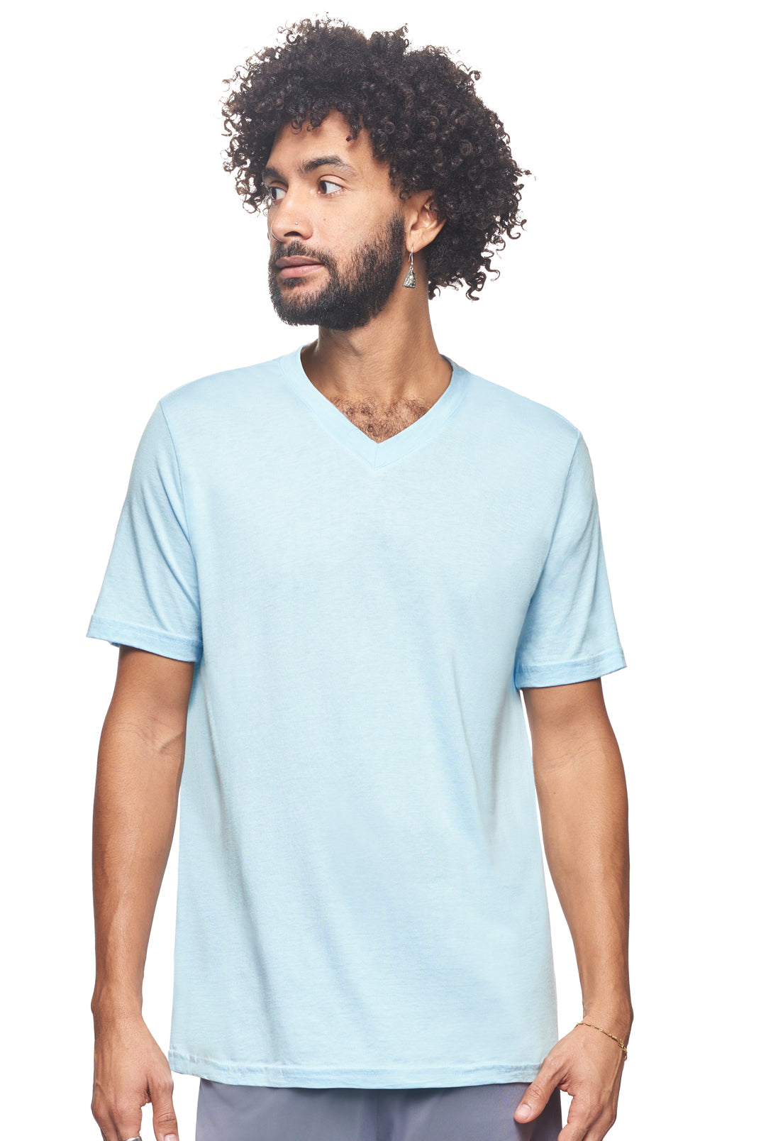 A male model with curly hair wearing the Men's MoCA V-Neck Tee in the color light blue, made from a luxurious blend of 50% LENZING Modal and 50% Combed Ring-Spun Cotton, showing the relaxed fit from a front view. This fashion-forward, more sustainable t-shirt is elevated, eco-friendly, made in the USA, and available for bulk purchase. #light-blue