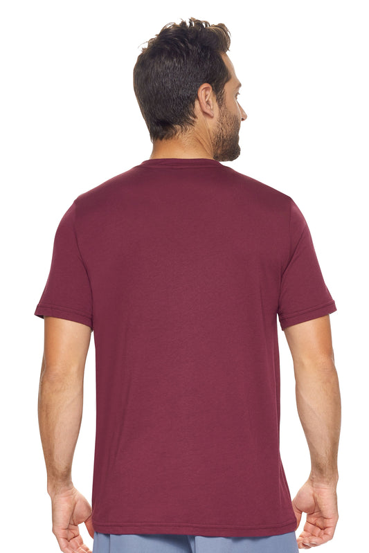 A male model with curly hair wearing the Men's MoCA V-Neck Tee in the color maroon, made from a luxurious blend of 50% LENZING Modal and 50% Combed Ring-Spun Cotton, showing the relaxed fit from a back view. This fashion-forward, more sustainable t-shirt is elevated, eco-friendly, made in the USA, and available for bulk purchase. #maroon