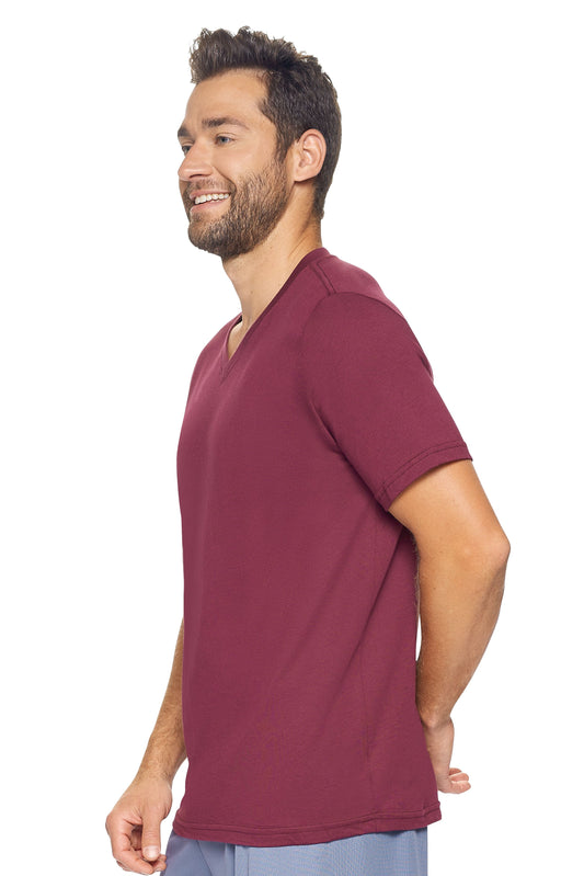 A male model with curly hair wearing the Men's MoCA V-Neck Tee in the color maroon, made from a luxurious blend of 50% LENZING Modal and 50% Combed Ring-Spun Cotton, showing the relaxed fit from a side view. This fashion-forward, more sustainable t-shirt is elevated, eco-friendly, made in the USA, and available for bulk purchase. #maroon