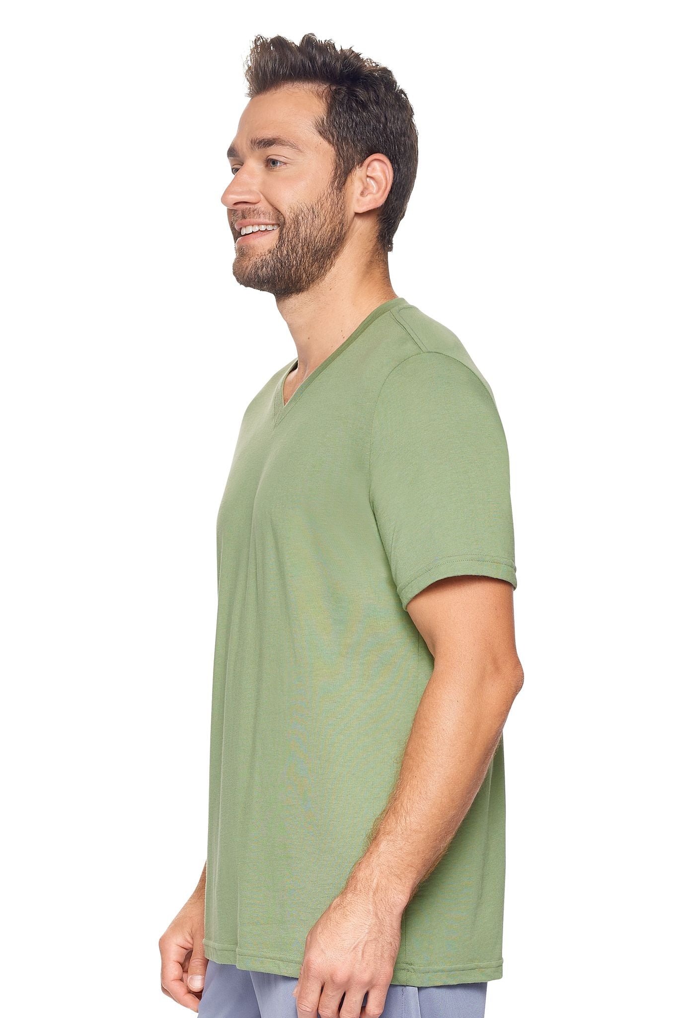 A male model with curly hair wearing the Men's MoCA V-Neck Tee in the color meadow, made from a luxurious blend of 50% LENZING Modal and 50% Combed Ring-Spun Cotton, showing the relaxed fit from a side view. This fashion-forward, more sustainable t-shirt is elevated, eco-friendly, made in the USA, and available for bulk purchase. #meadow