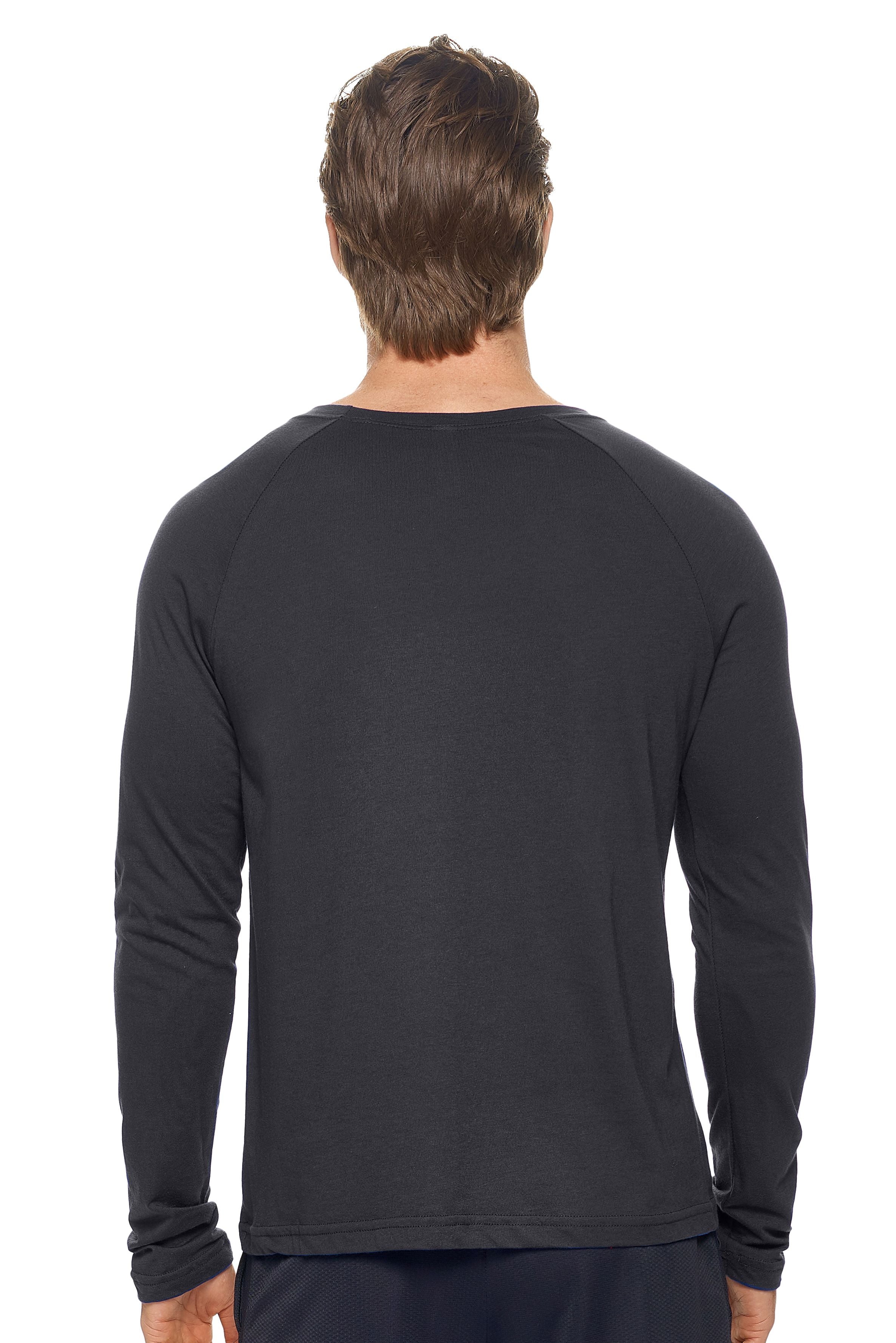 A male model with dirty blonde hair wearing the men's MoCA Long Sleeve Raglan Tee in the color black, made from a luxurious blend of 50% LENZING Modal and 50% Combed Ring-Spun Cotton, showing the relaxed fit from a back view. This shirt is elevated, eco-friendly, made in the USA, and available for bulk purchase. #black