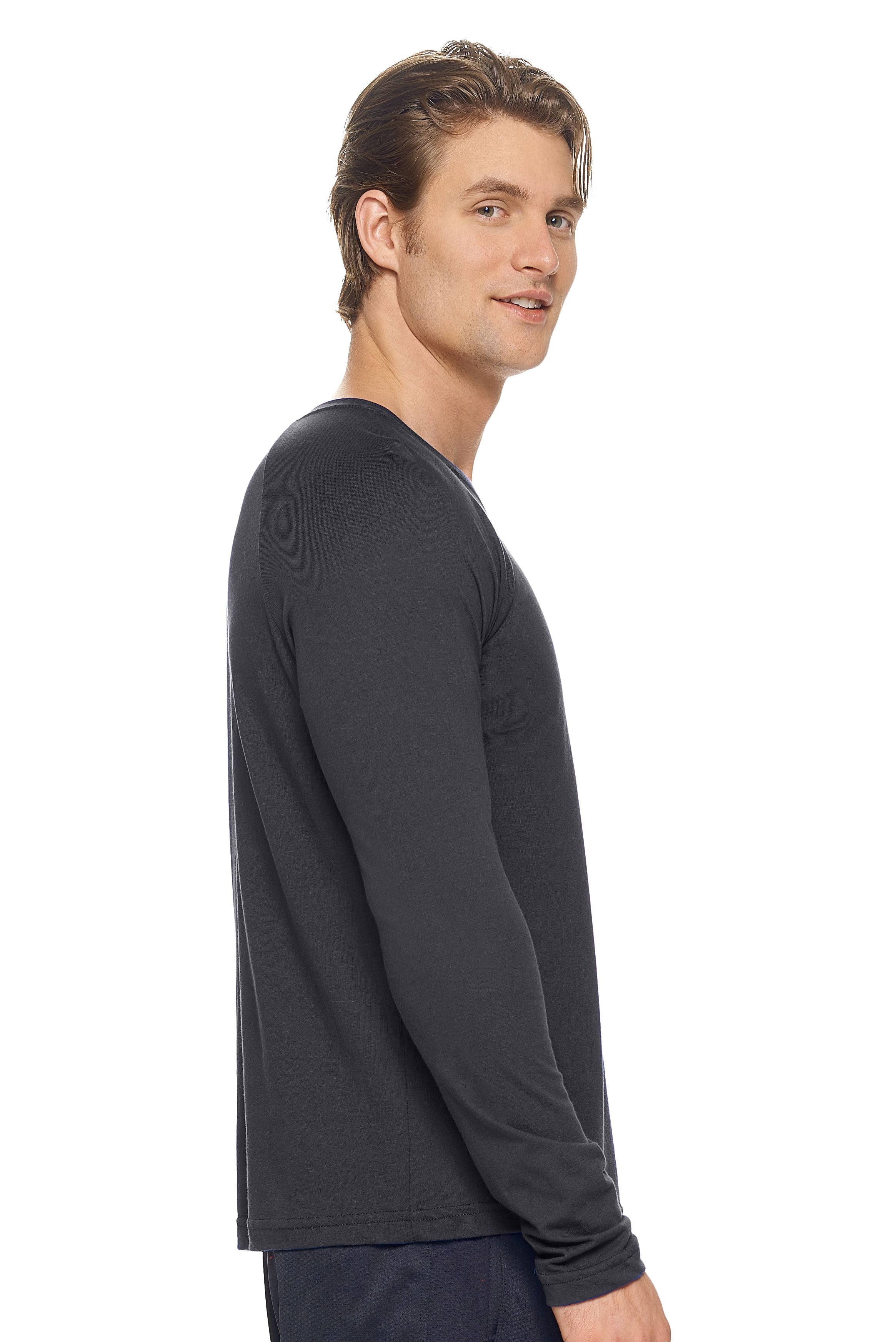 A male model with dirty blonde hair wearing the men's MoCA Long Sleeve Raglan Tee in the color black, made from a luxurious blend of 50% LENZING Modal and 50% Combed Ring-Spun Cotton, showing the relaxed fit from a side view. This shirt is elevated, eco-friendly, made in the USA, and available for bulk purchase. #black
