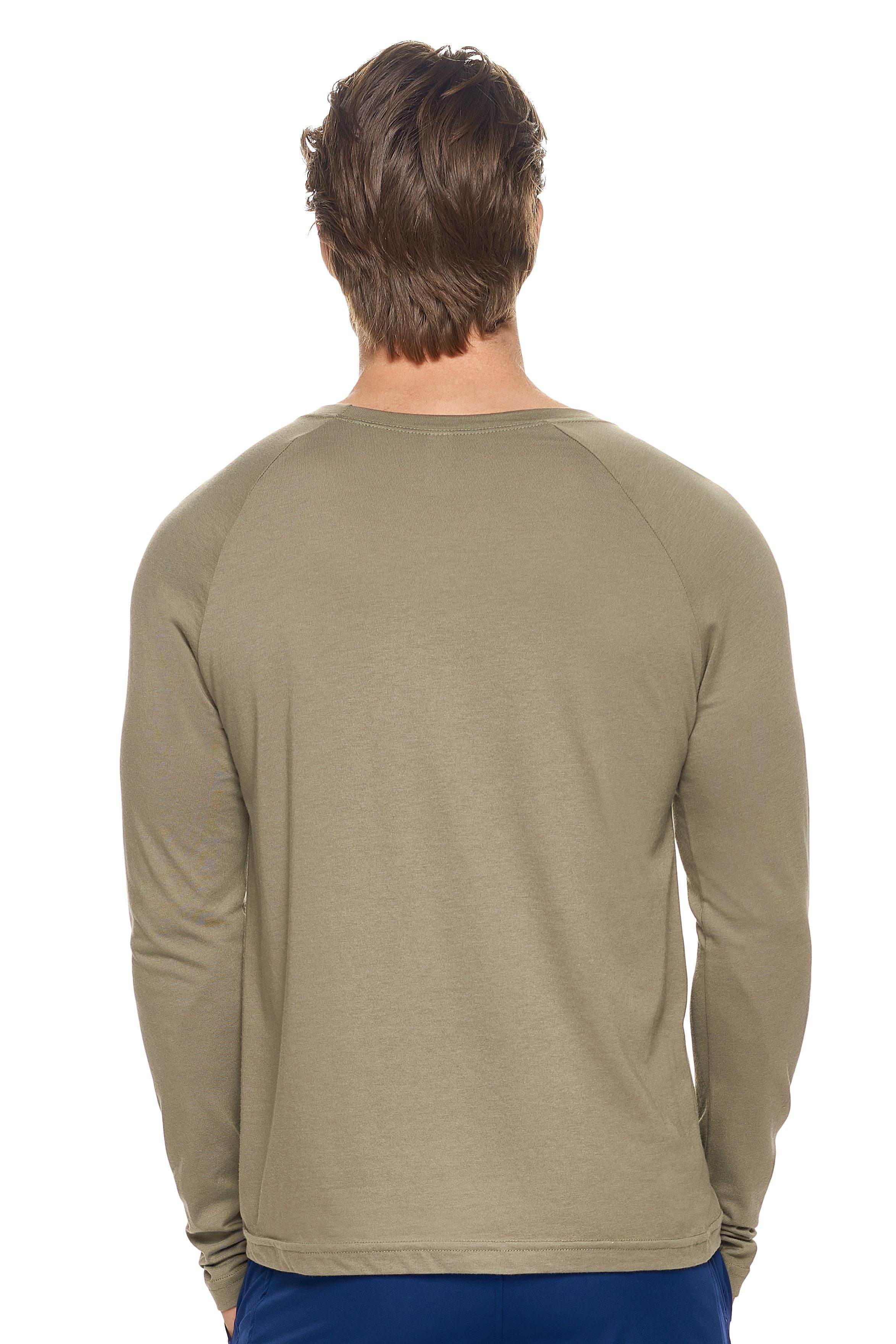 A male model with dirty blonde hair wearing the men's MoCA Long Sleeve Raglan Tee in the color olive, made from a luxurious blend of 50% LENZING Modal and 50% Combed Ring-Spun Cotton, showing the relaxed fit from a back view. This shirt is elevated, eco-friendly, made in the USA, and available for bulk purchase. #olive